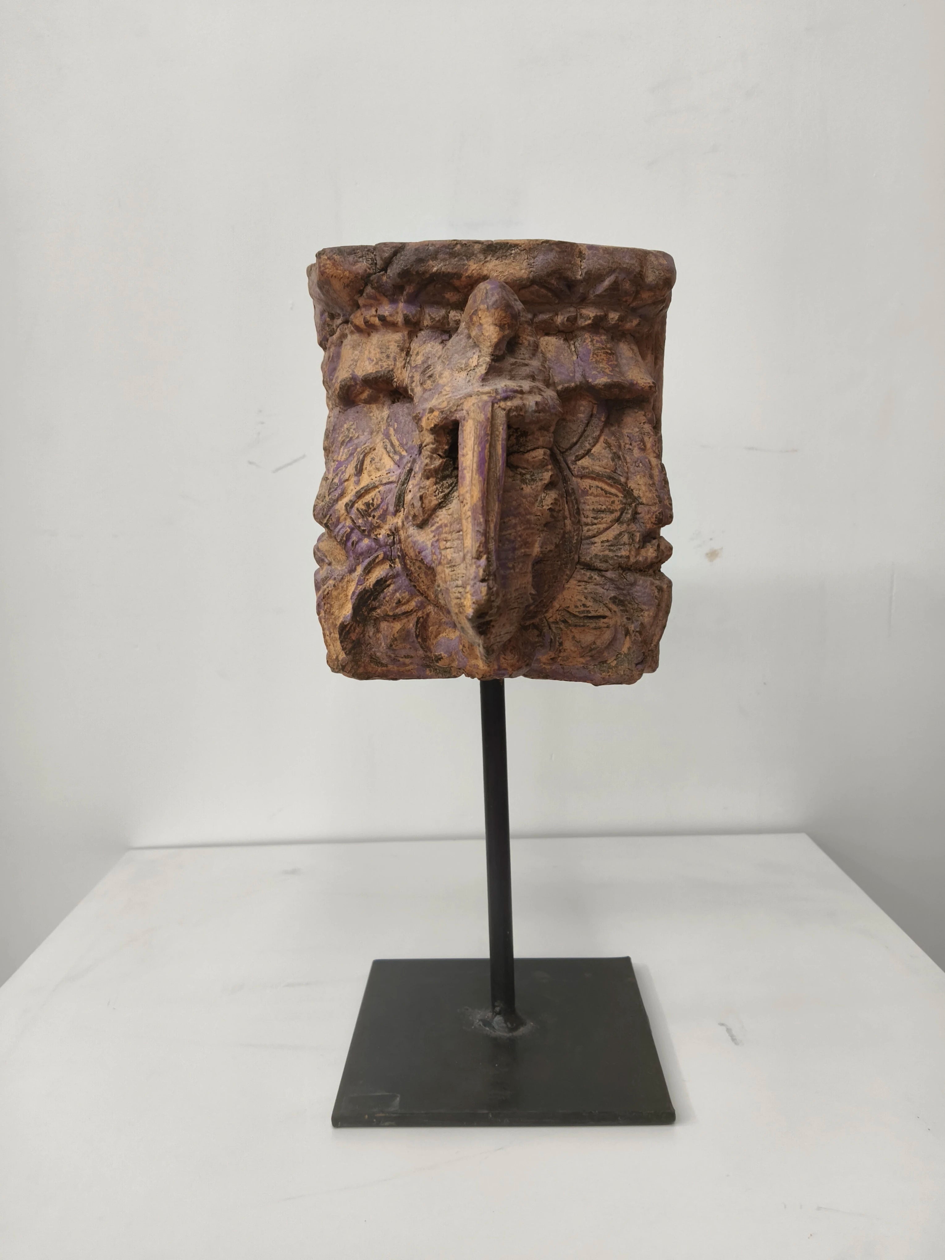Large wooden candle stand with carved elephant design on a black metal base