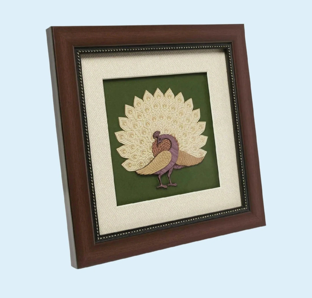 Framed textile art depicting a stylized peacock with intricate cream and purple feathers