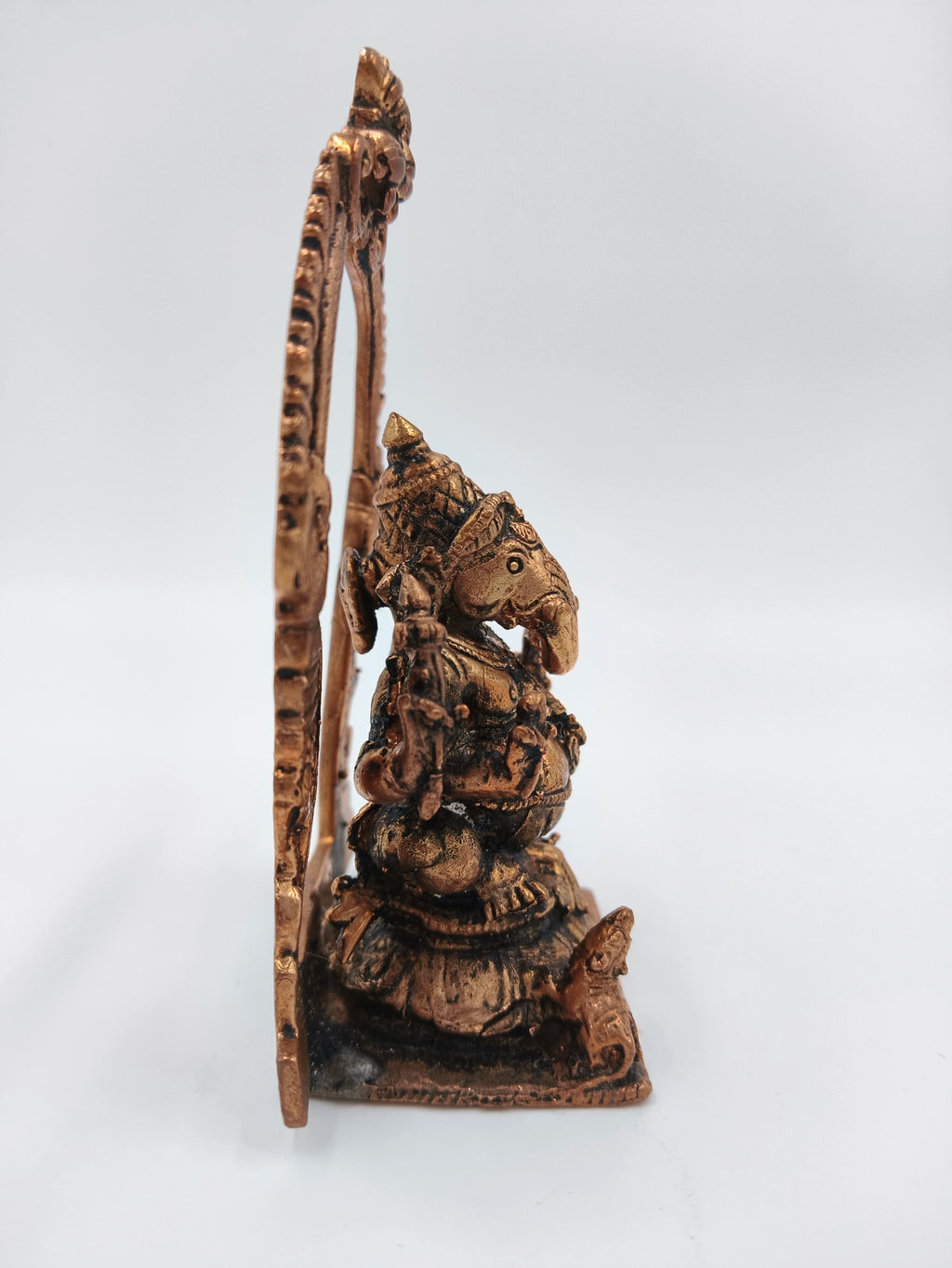 Side view of copper brass Ganesh statue with decorative arch
