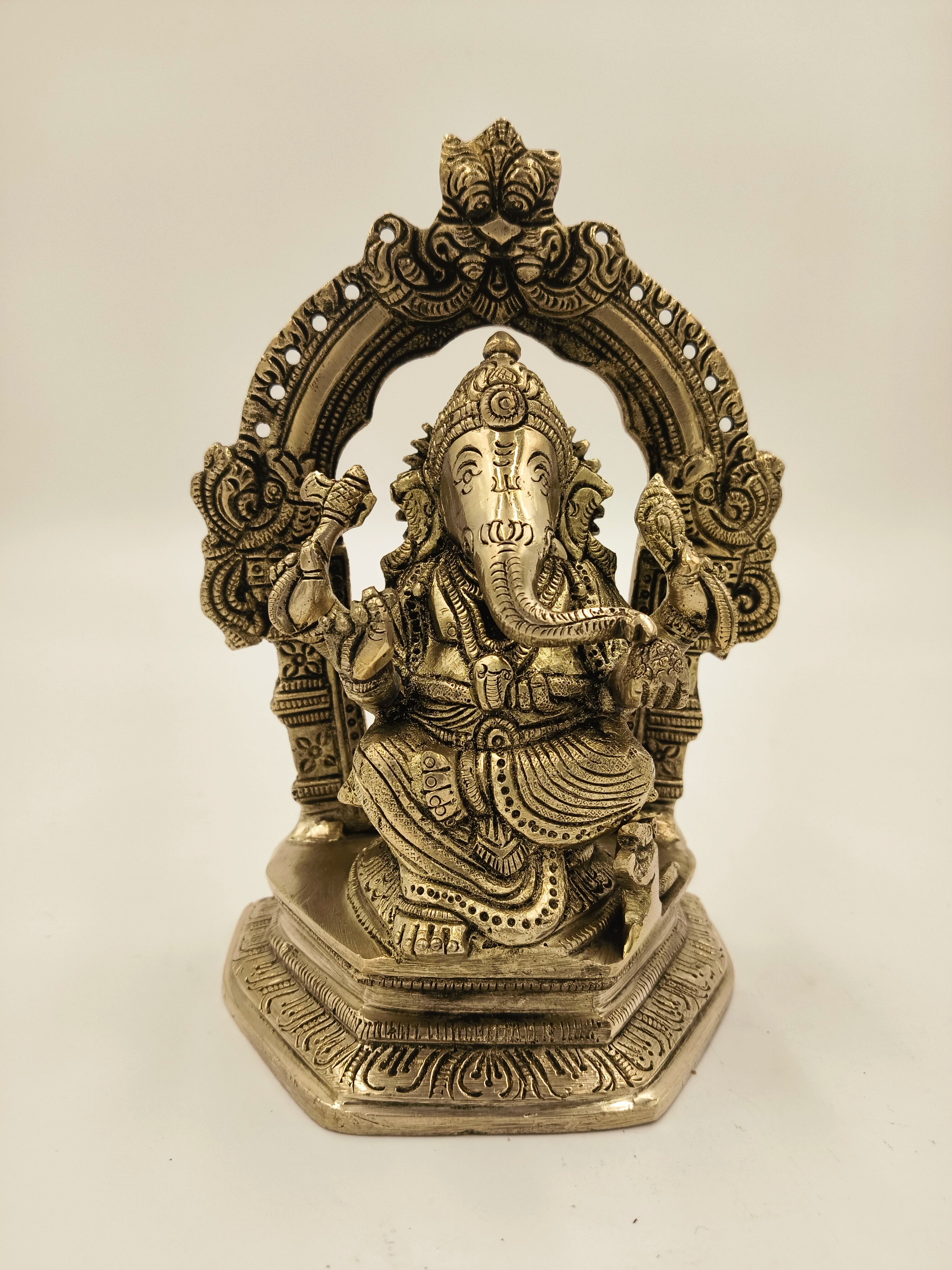 Large brass statue of Ganesh seated with ornate arch and detailed carvings