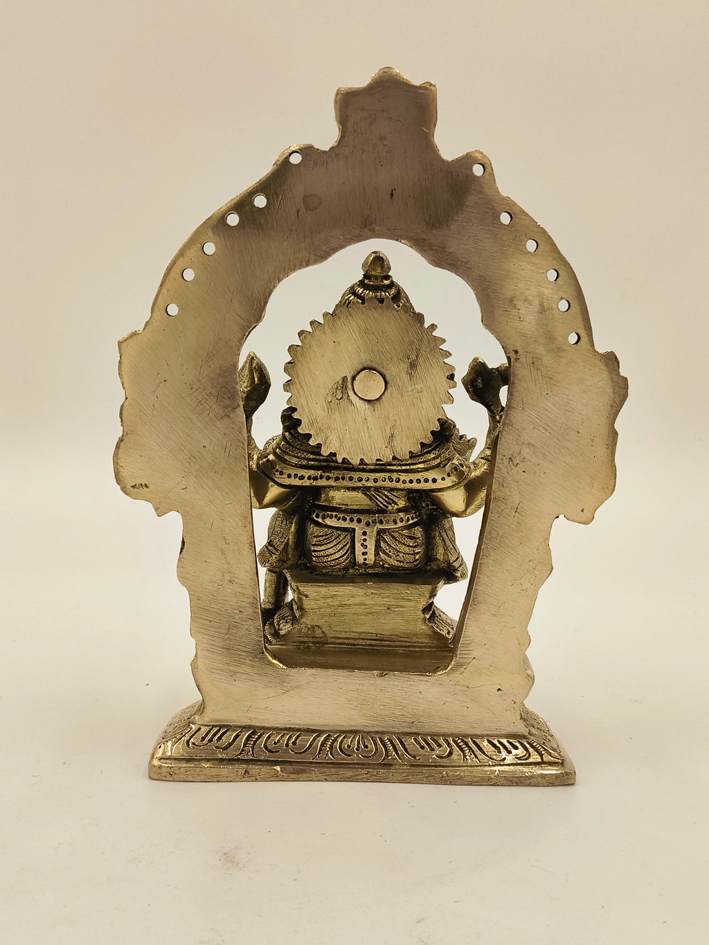 Back view of large brass Ganesh idol with decorative arch frame
