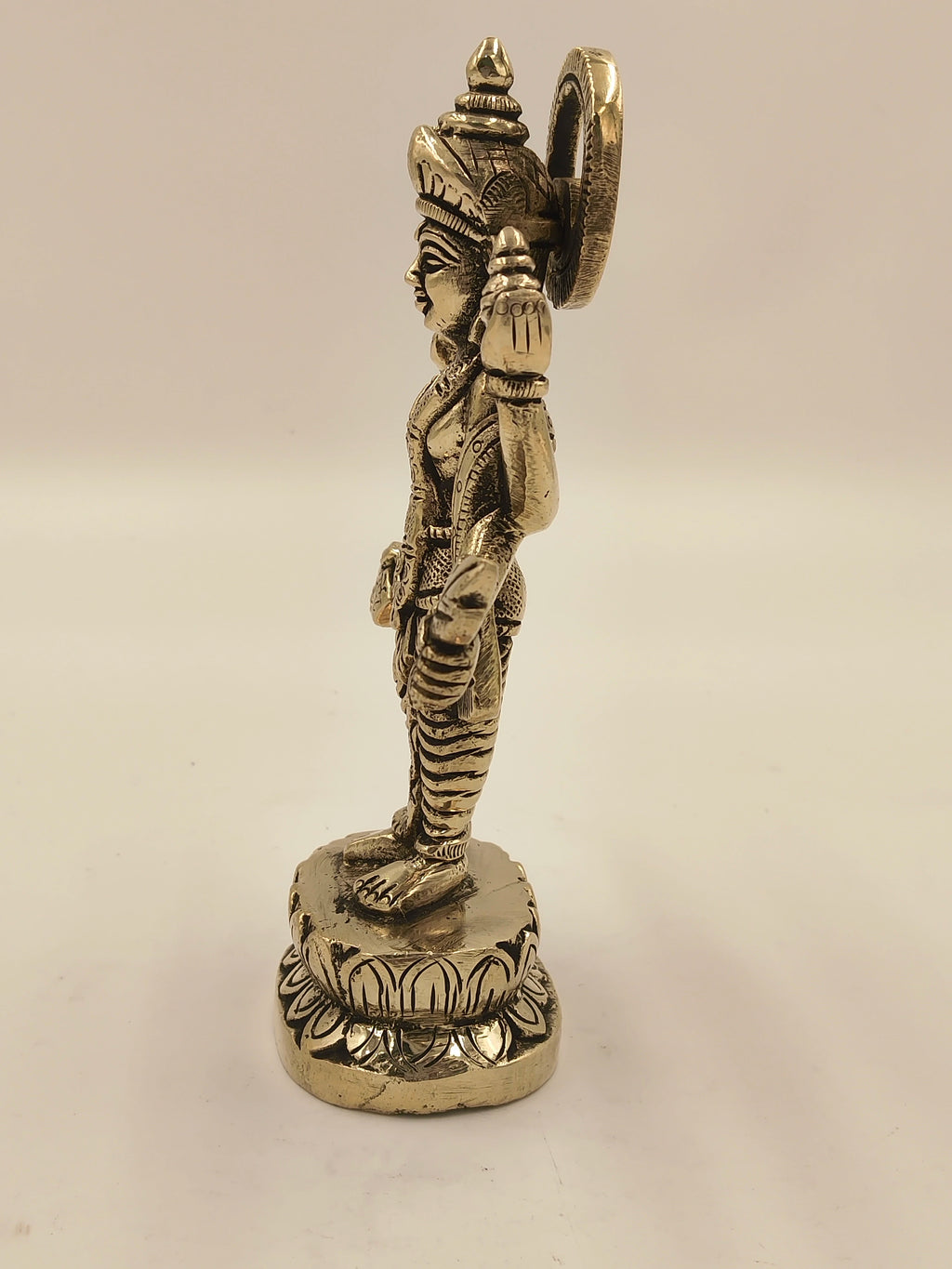 Side view of medium brass Narayana statue standing on decorative base