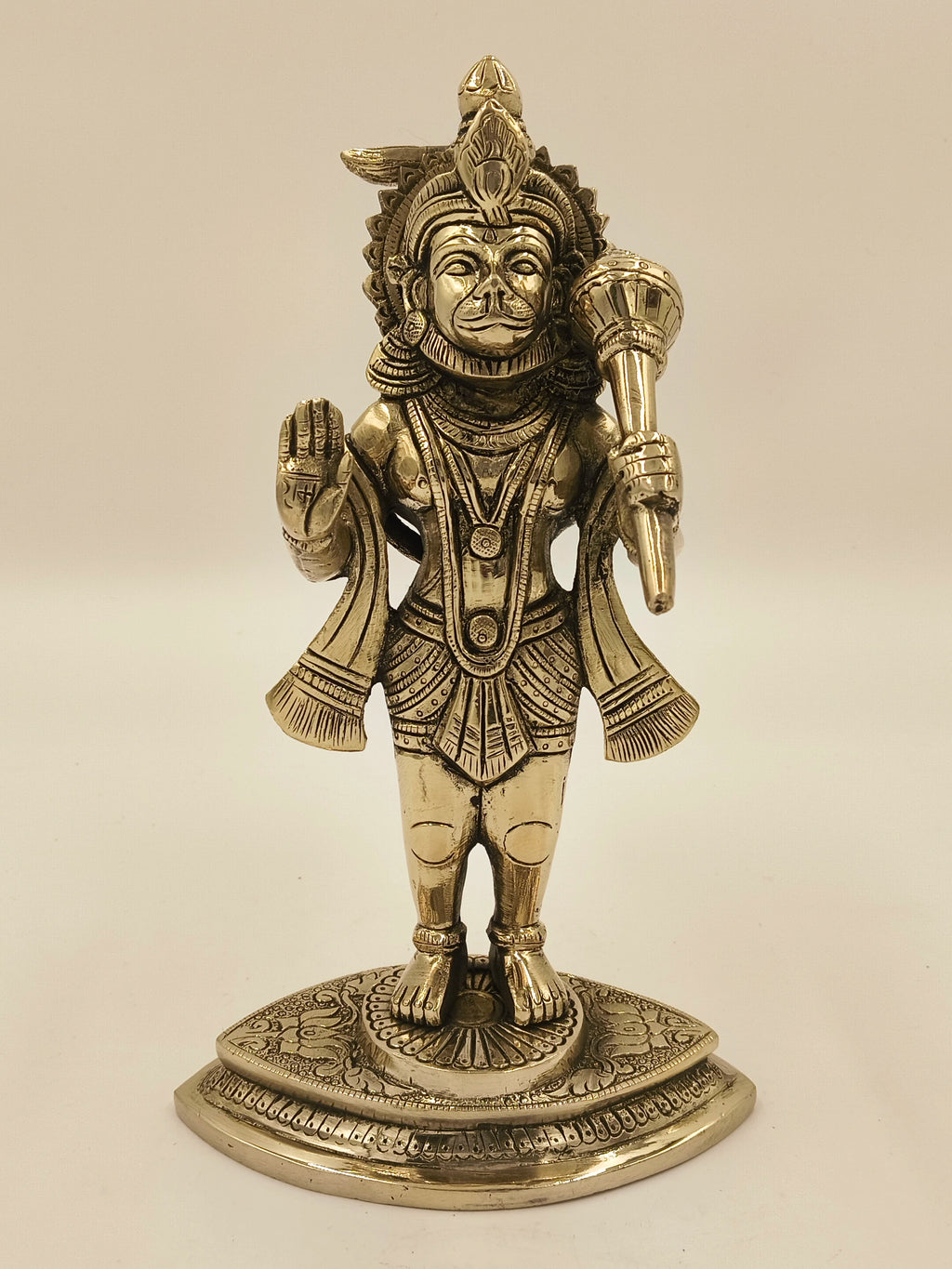 Brass Hanuman sculpture standing on decorated base with raised hand and mace