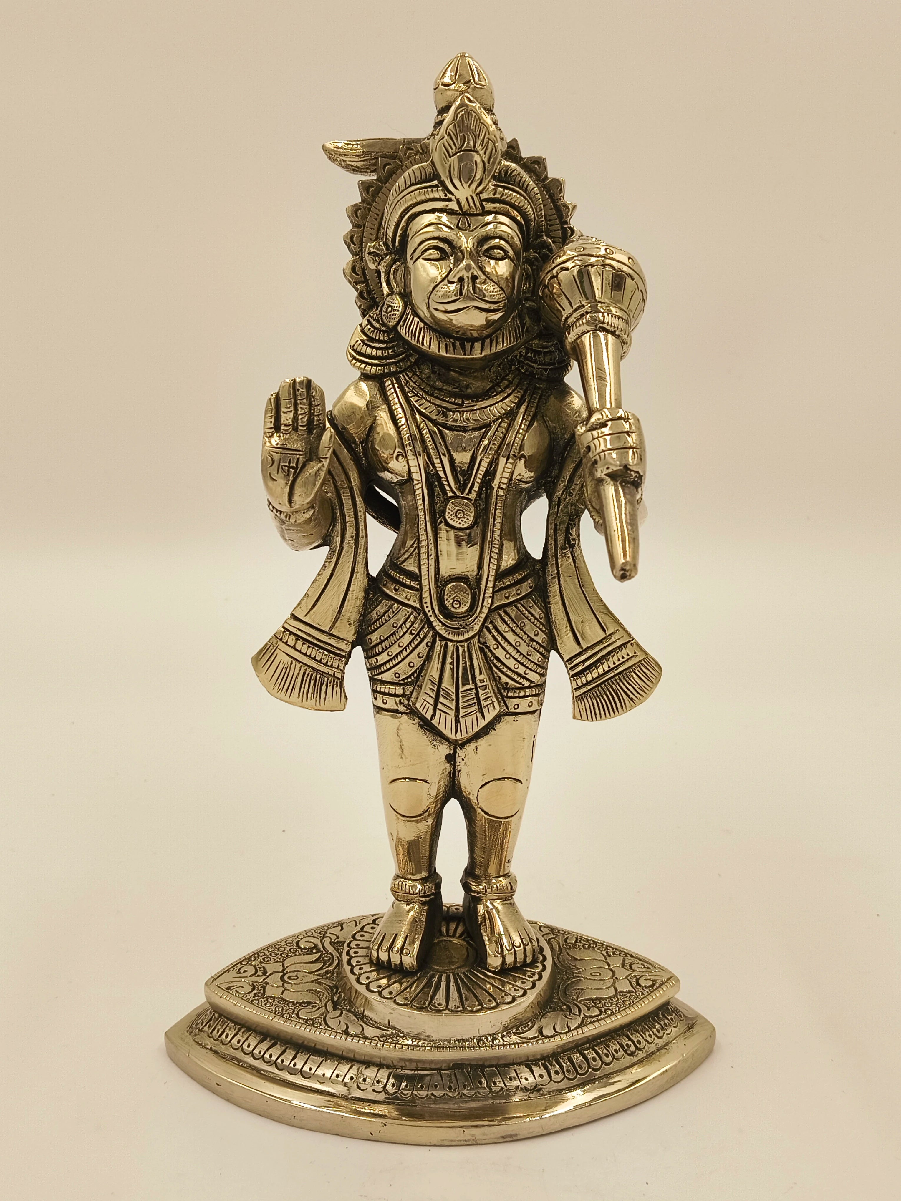 Brass Hanuman sculpture standing on decorated base with raised hand and mace