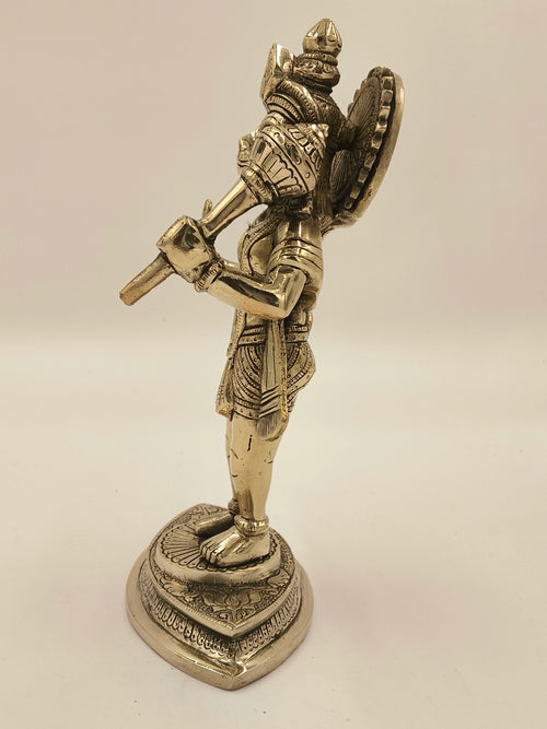 Side view of brass Hanuman statue playing flute on decorative base