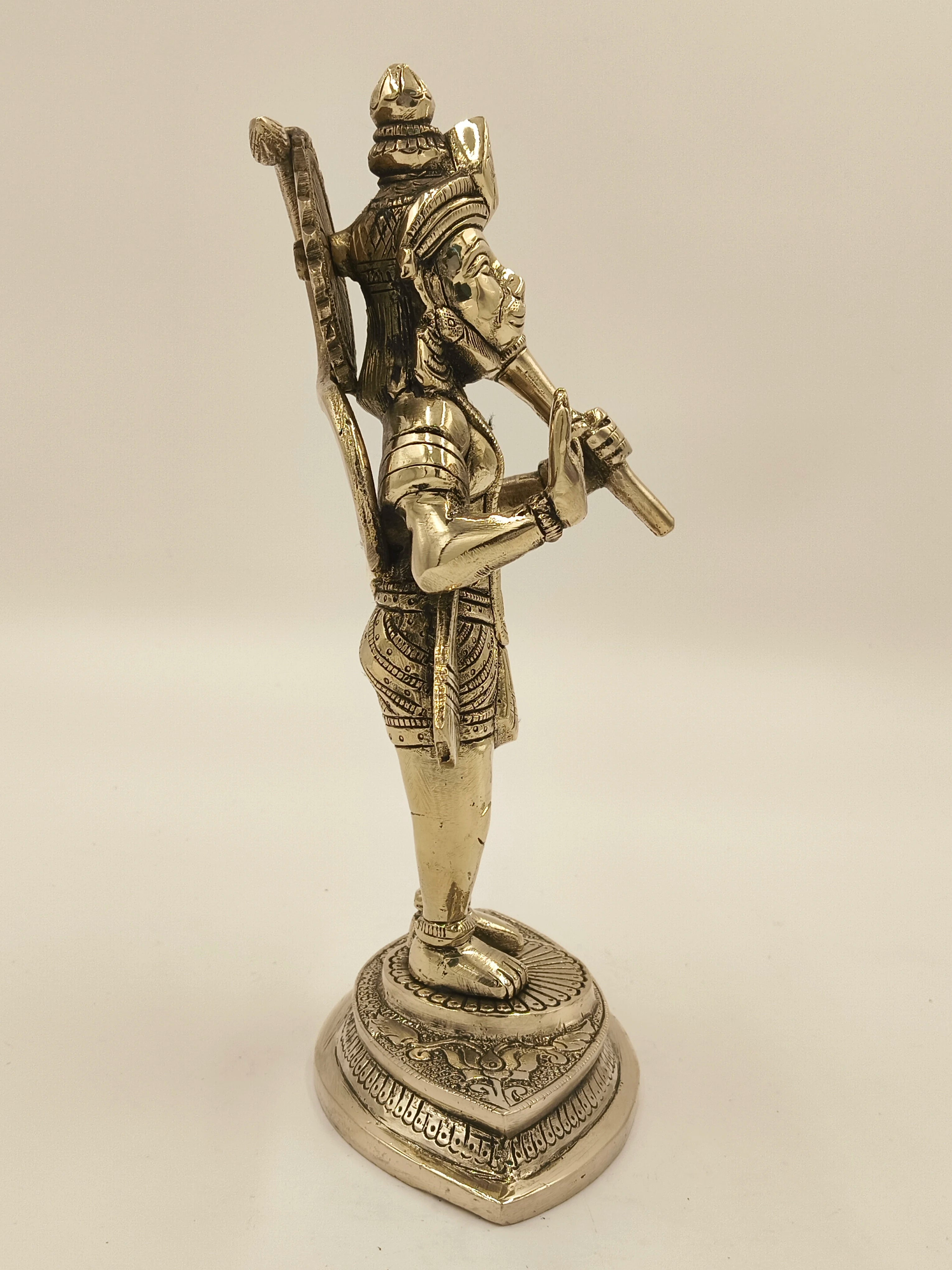 Side view of brass statue of Hanuman holding a mace on decorative base