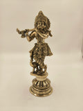 Large brass statue of Krishna playing flute on decorative pedestal