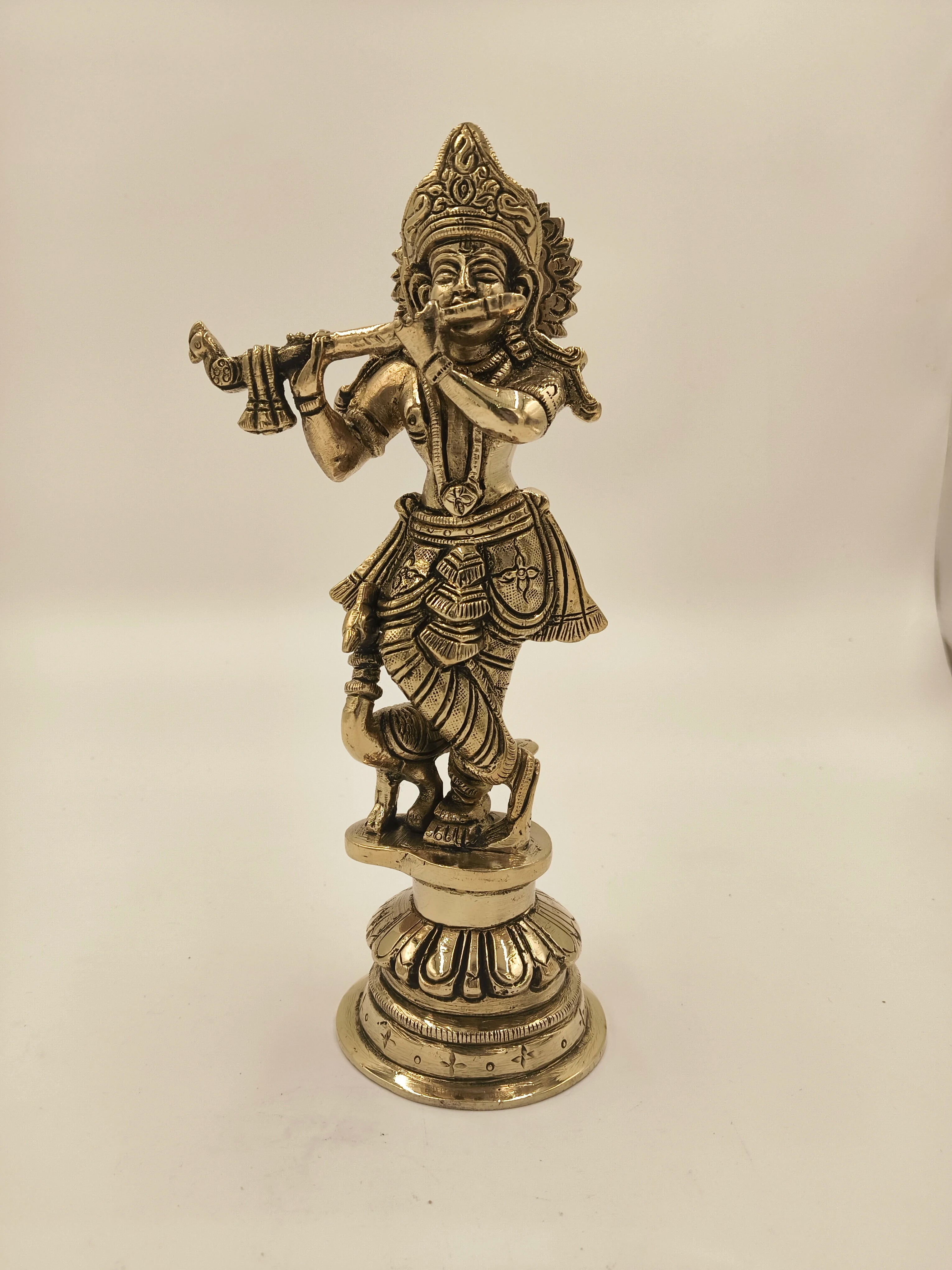 Large brass statue of Krishna playing flute on decorative pedestal
