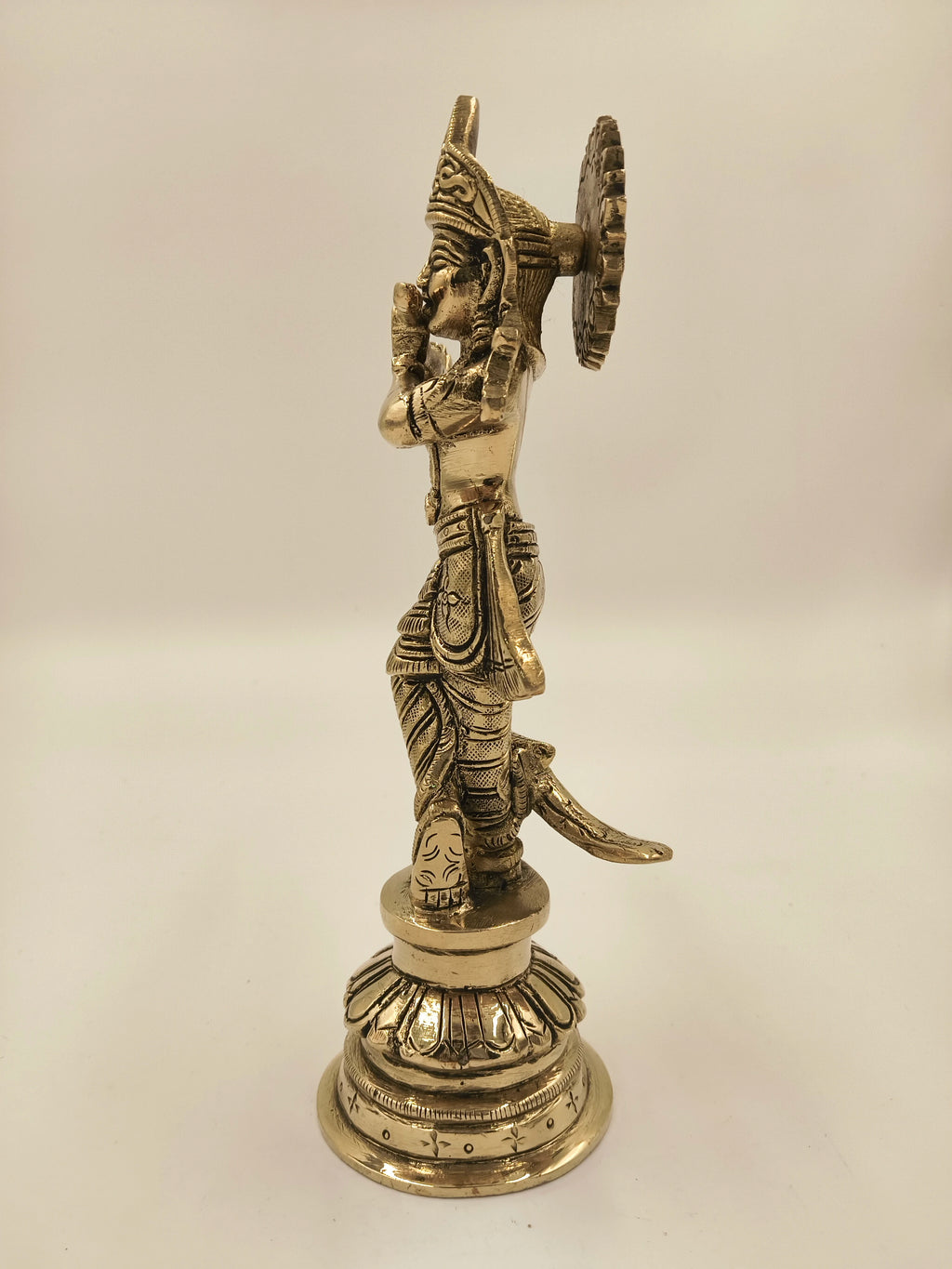 Side view of large brass sculpture of Krishna as Gokula Nandana standing on ornate pedestal