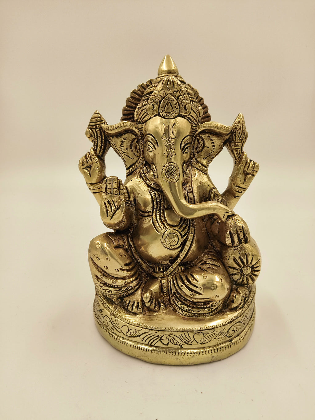 Large brass Swarna Ganesh statue with intricate detailing seated on a decorated base
