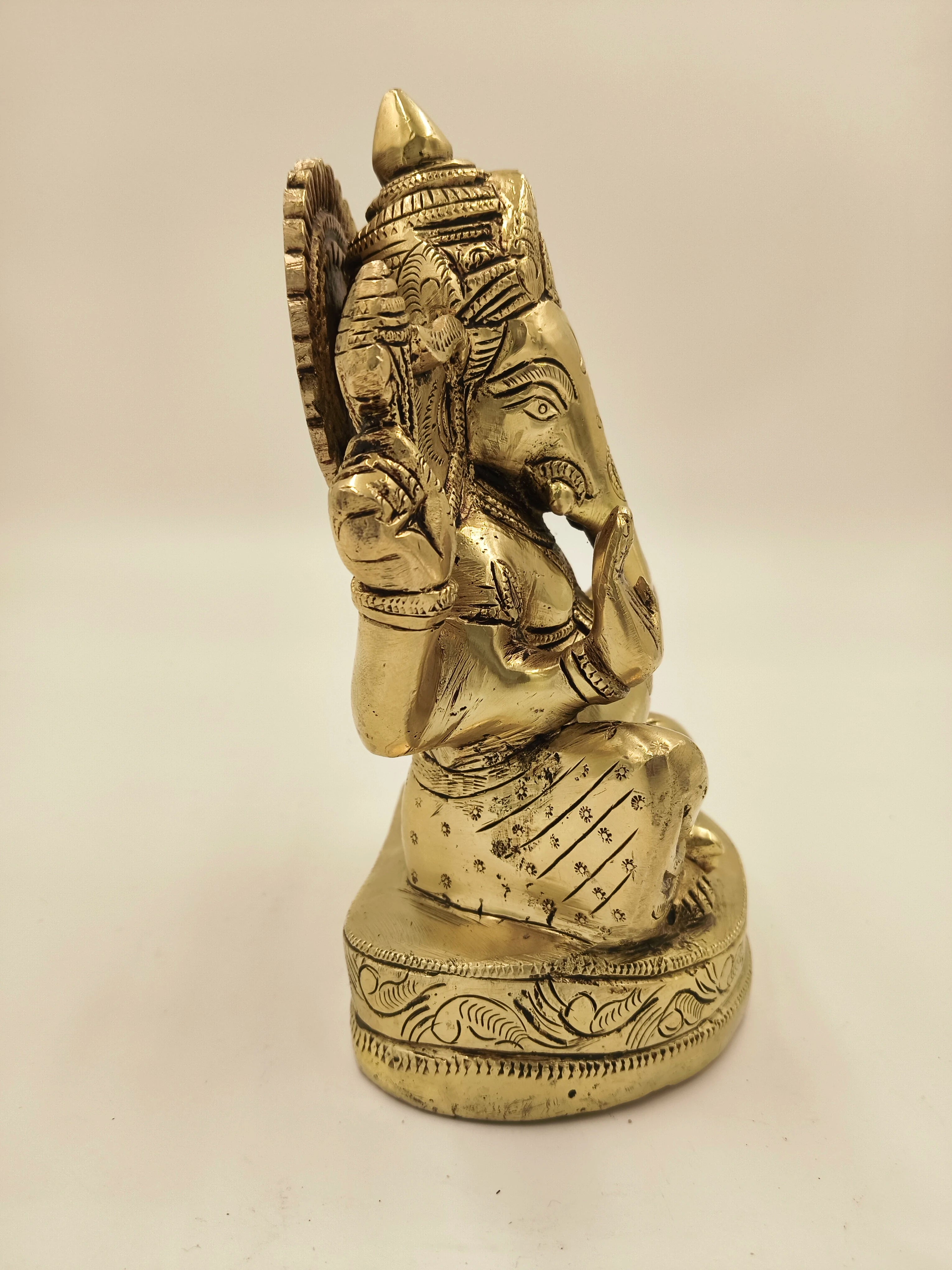 Side view of a large brass Swarna Ganesh statue with intricate details