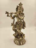 Large brass statue of Krishna playing flute with peacock beside him