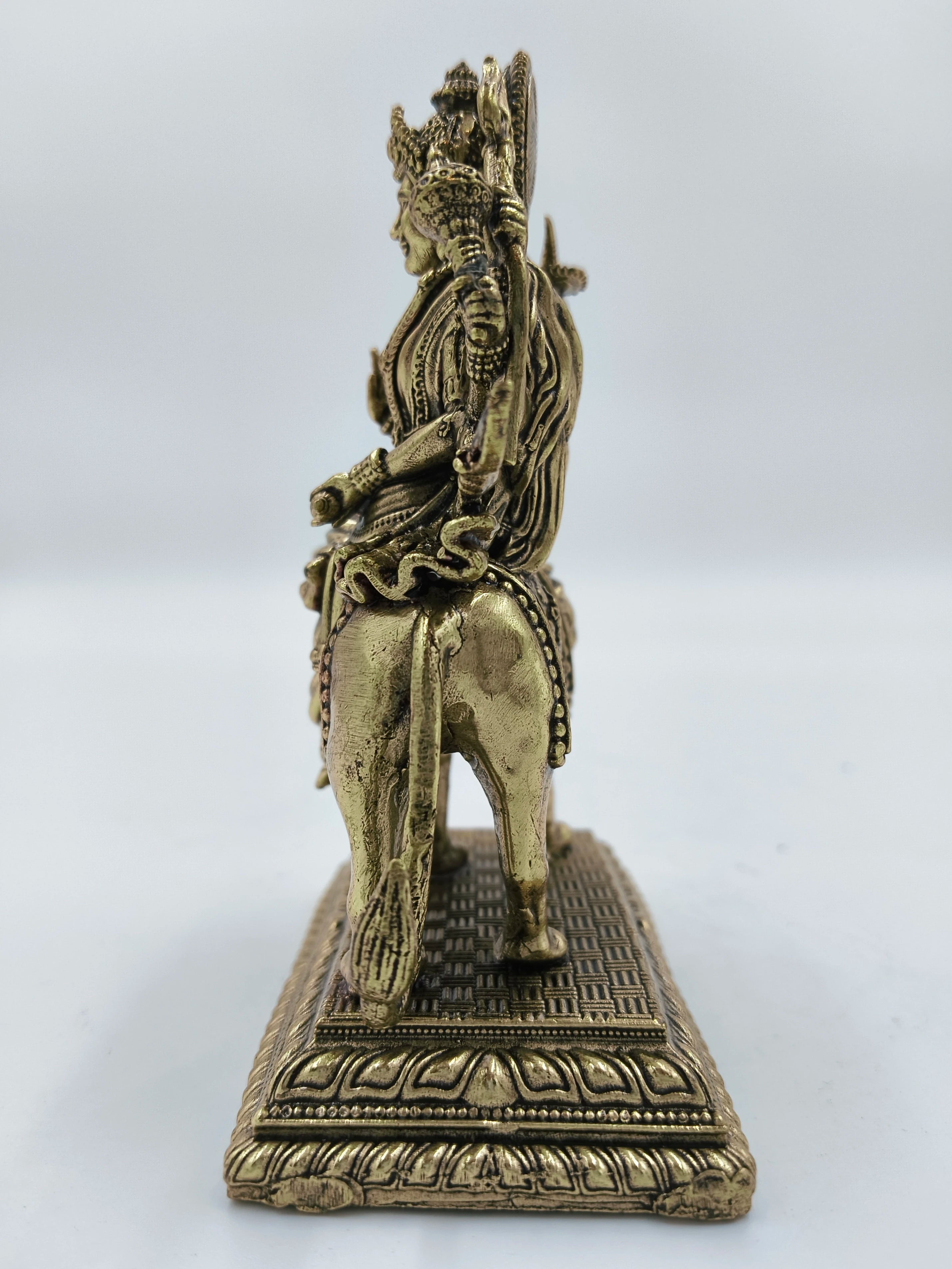 Side view of a medium brass Durga statue seated on a lion with detailed base