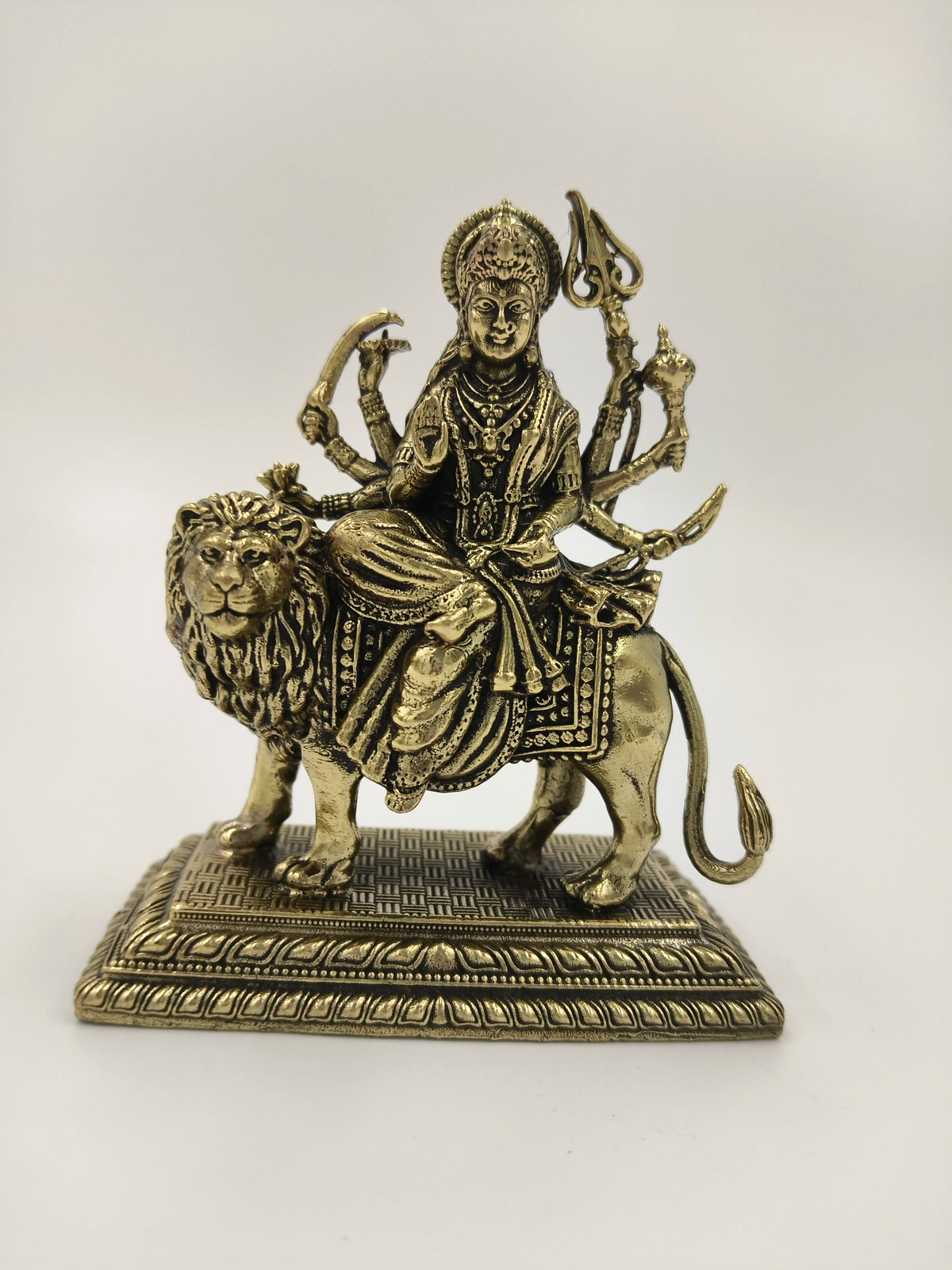 Small brass sculpture of Hindu goddess Durga riding a lion on a detailed base