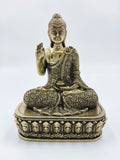 Small brass Buddha statue seated cross-legged on decorative pedestal