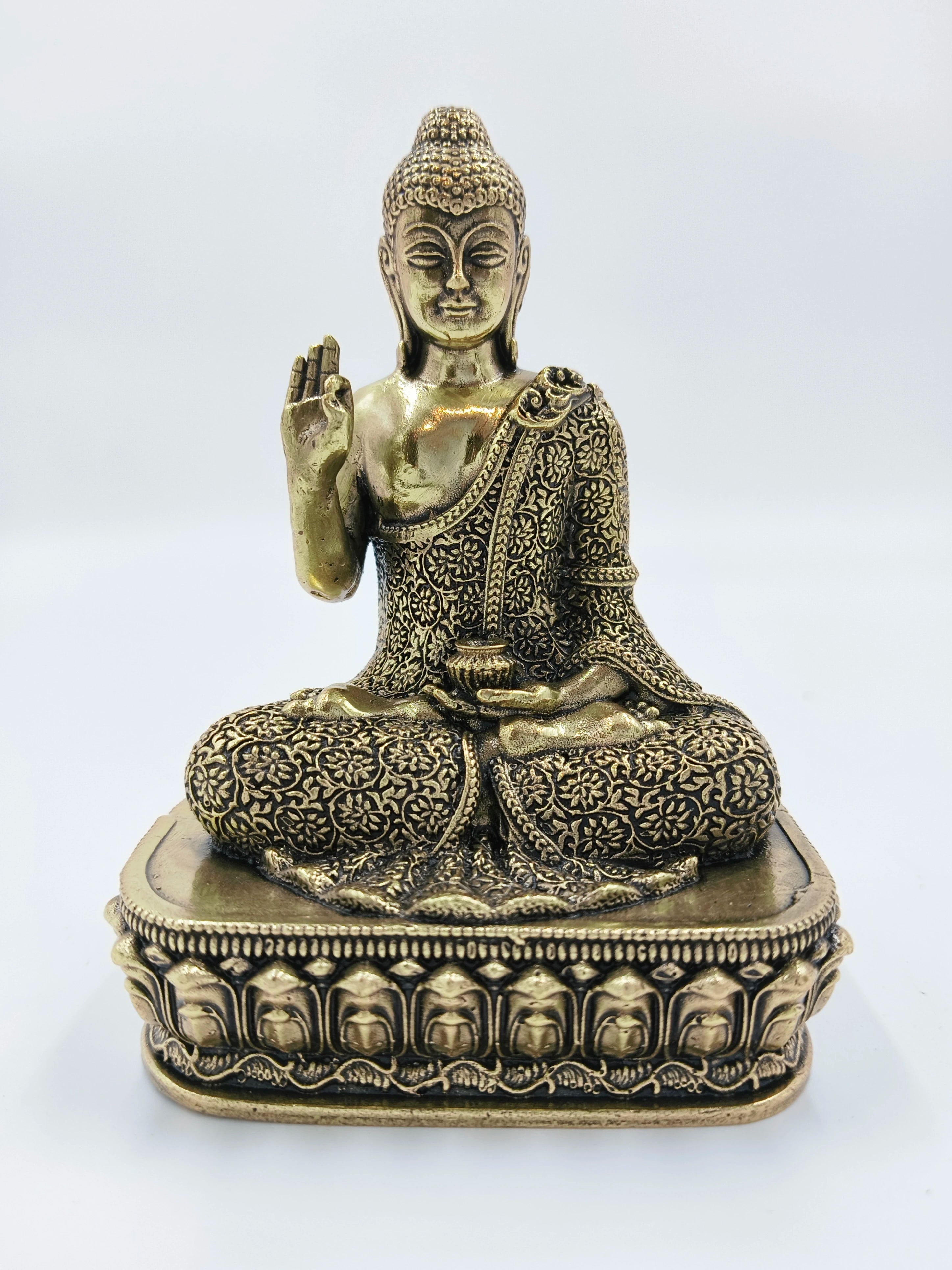 Small brass Buddha statue seated cross-legged on decorative pedestal