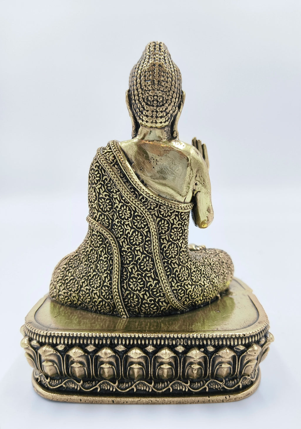 Back view of small brass Buddha statue seated on detailed base