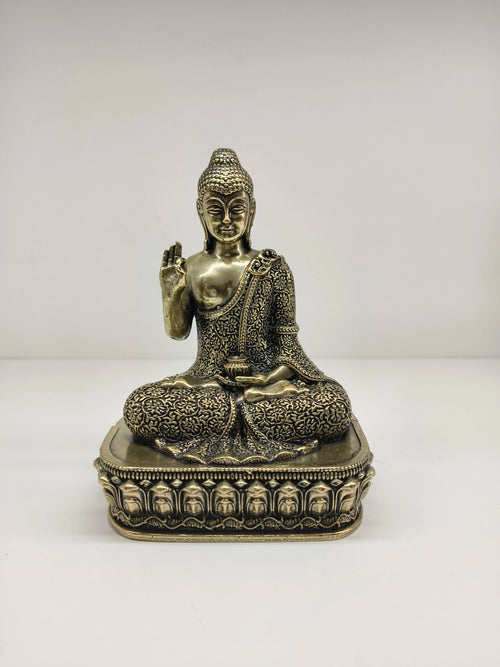 Small brass Buddha statue seated on an ornate pedestal, front view
