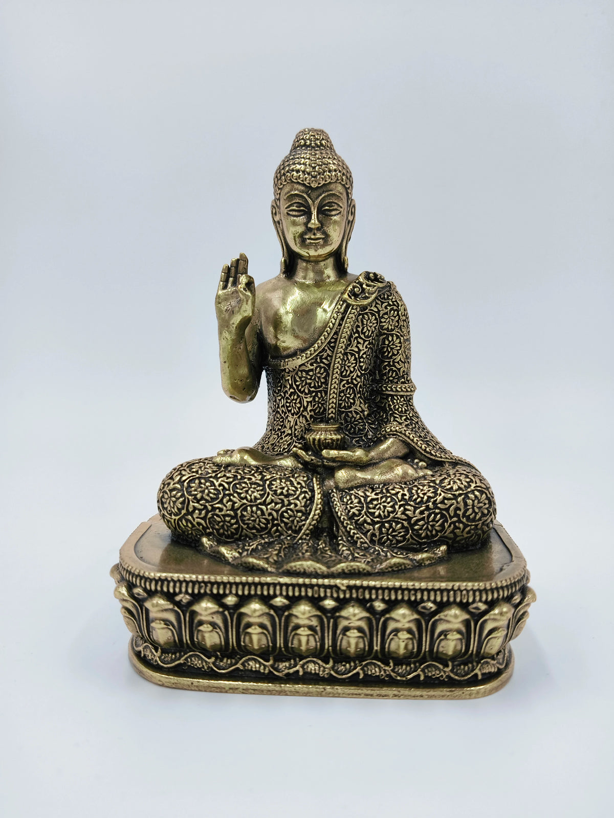 Small brass Buddha statue seated on an ornate pedestal, front view