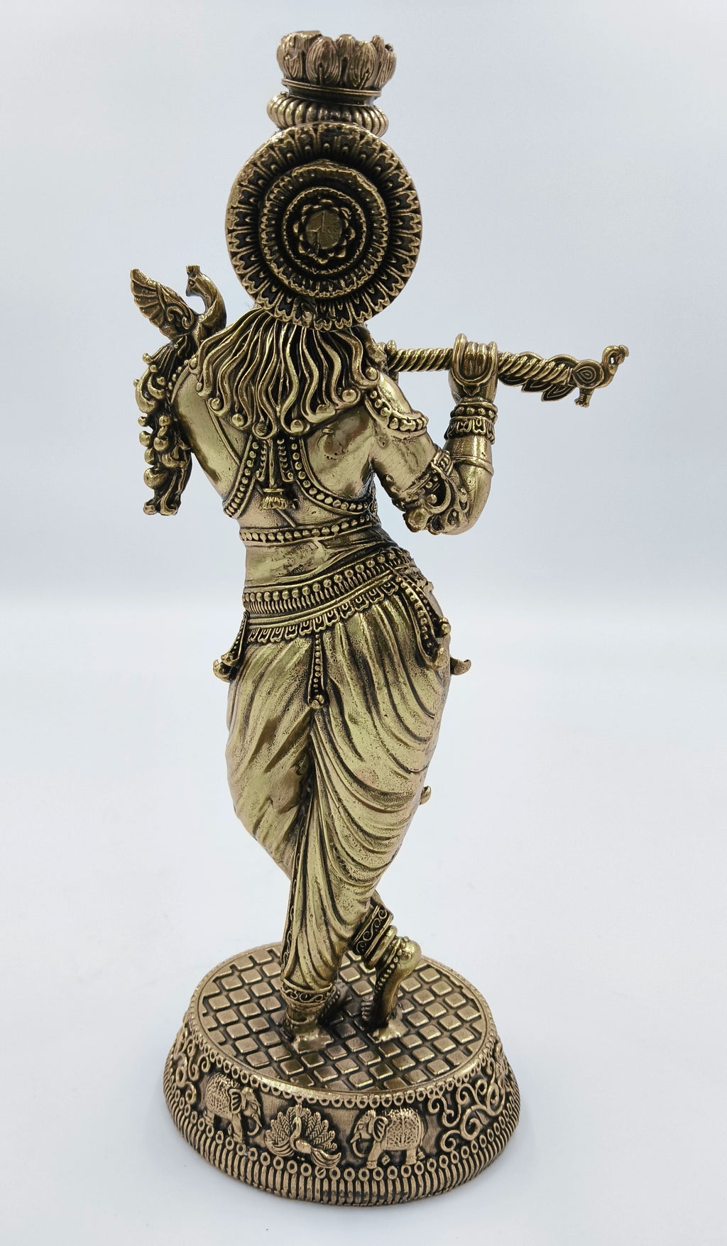 Rear view of large brass Krishna statue playing flute with detailed base