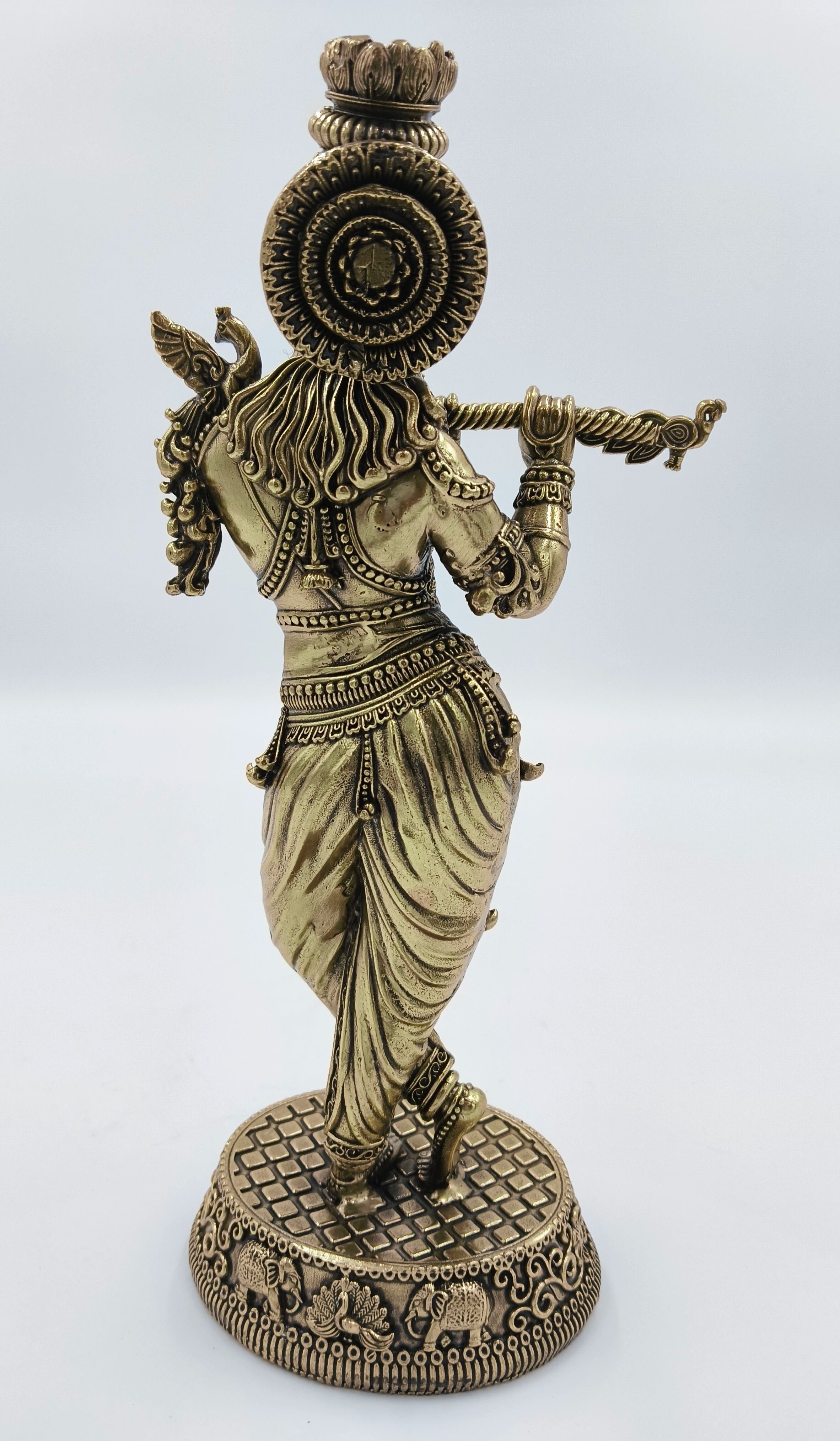 Rear view of large brass Krishna statue playing flute with detailed base