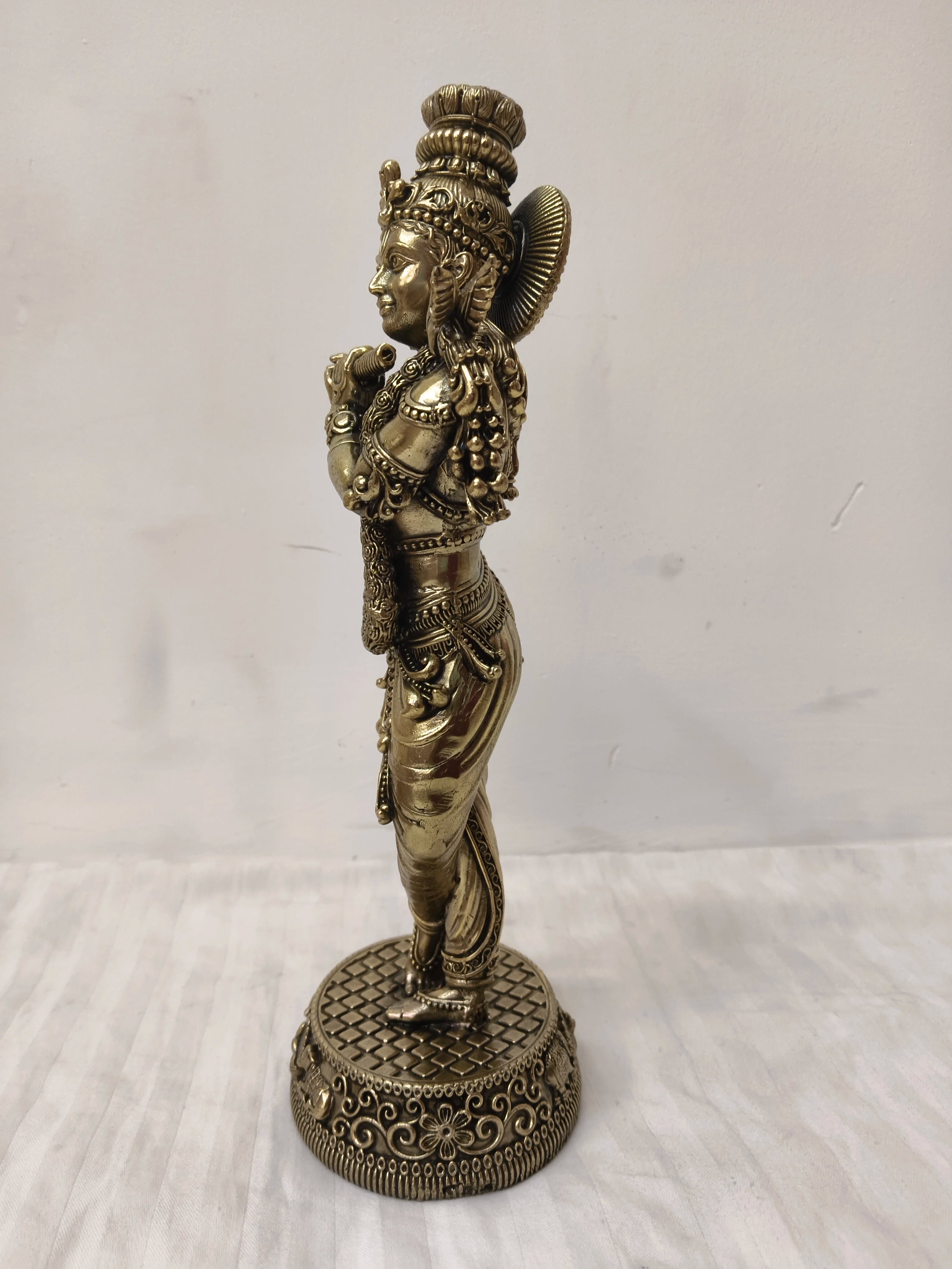 Side view of a large brass Venumadhava Krishna statue on decorative base