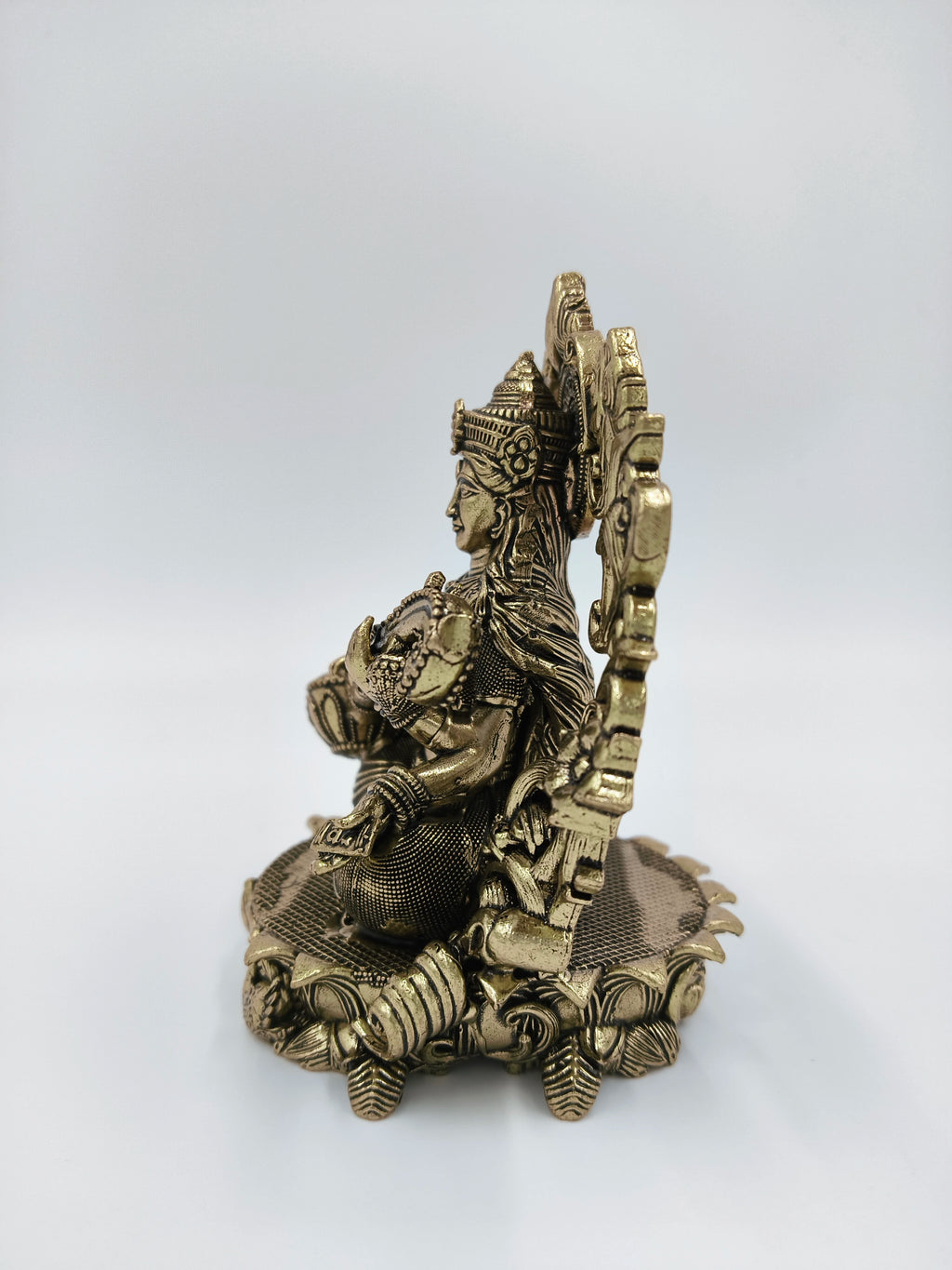Side view of small brass Saraswathi deity sculpture on decorative base