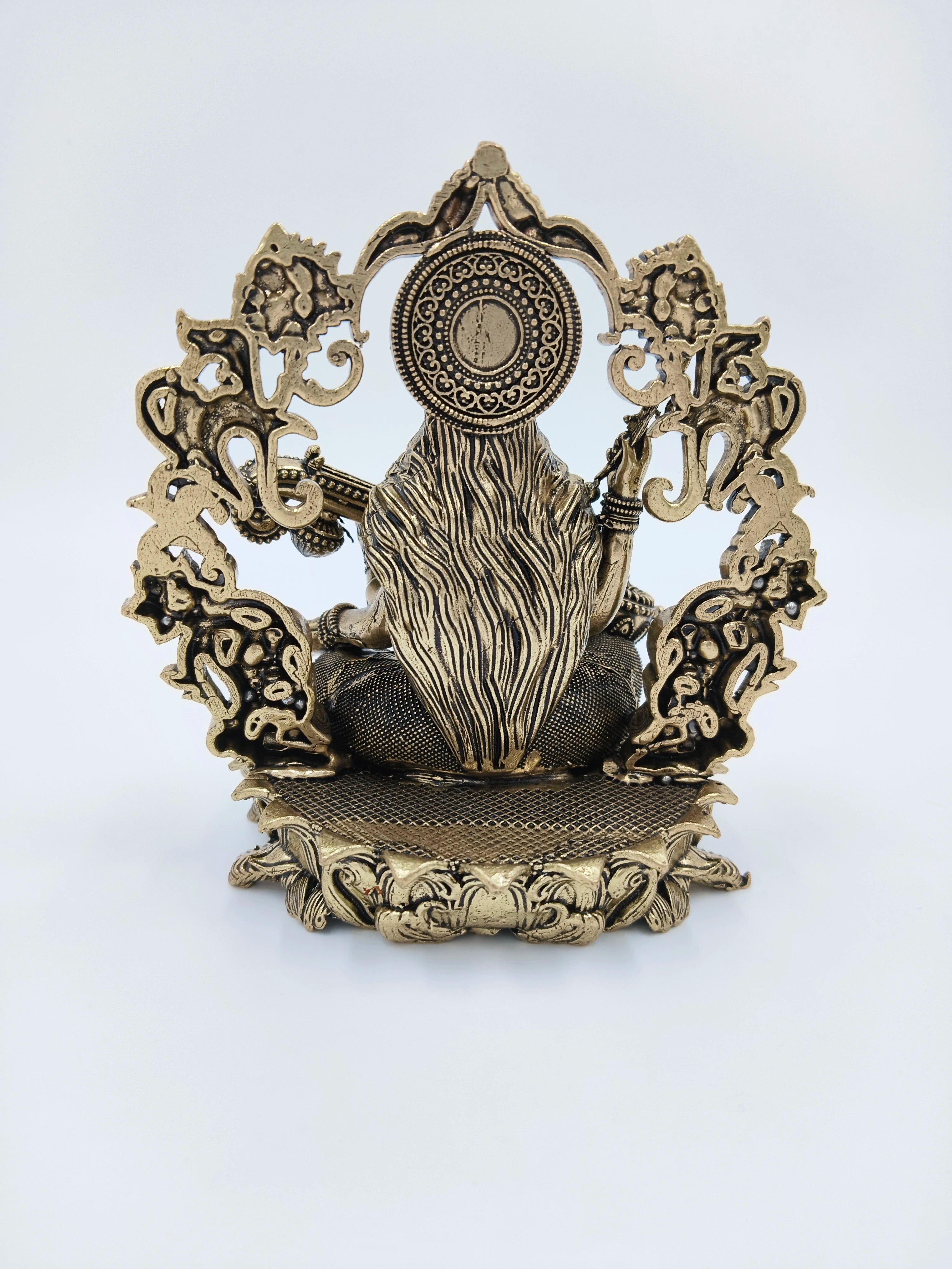 Back view of small brass Saraswathi figurine with ornate arch and detailed hair