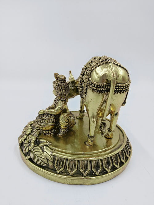 Brass sculpture of Krishna with cow in seated and standing poses on decorative base
