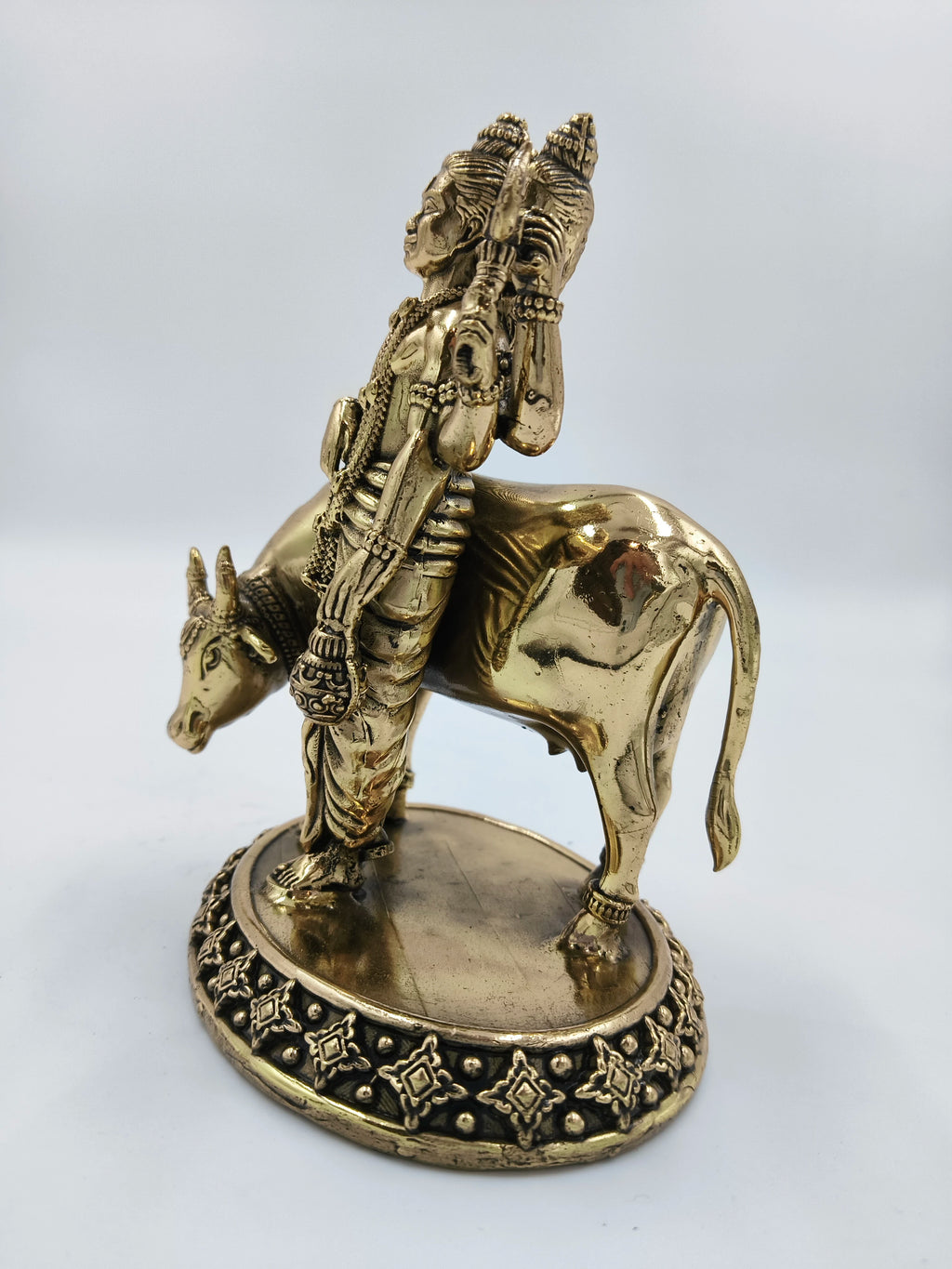 Brass statue of deity Dattatreya standing with cow on decorative base