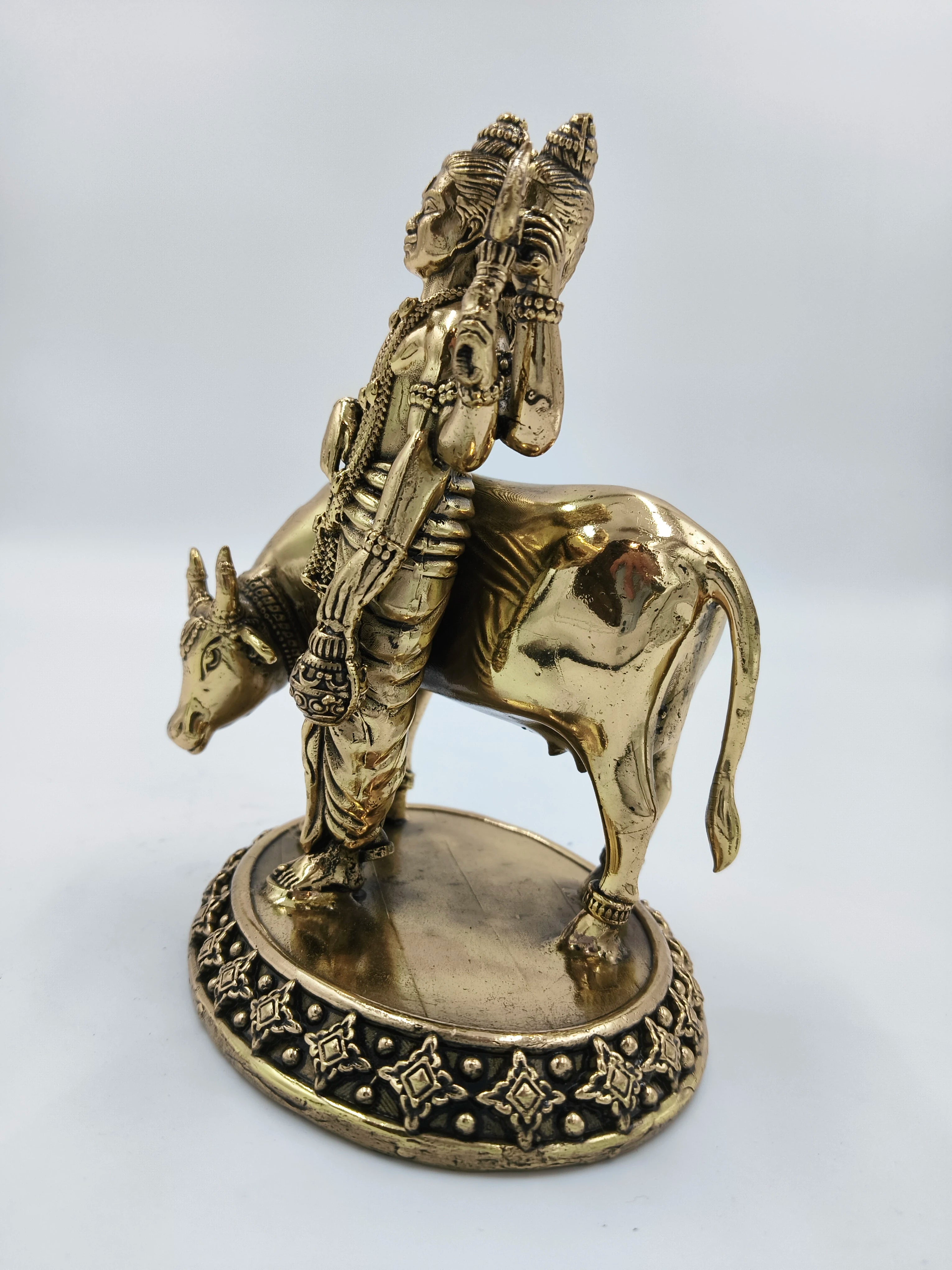 Brass statue of deity Dattatreya standing with cow on decorative base