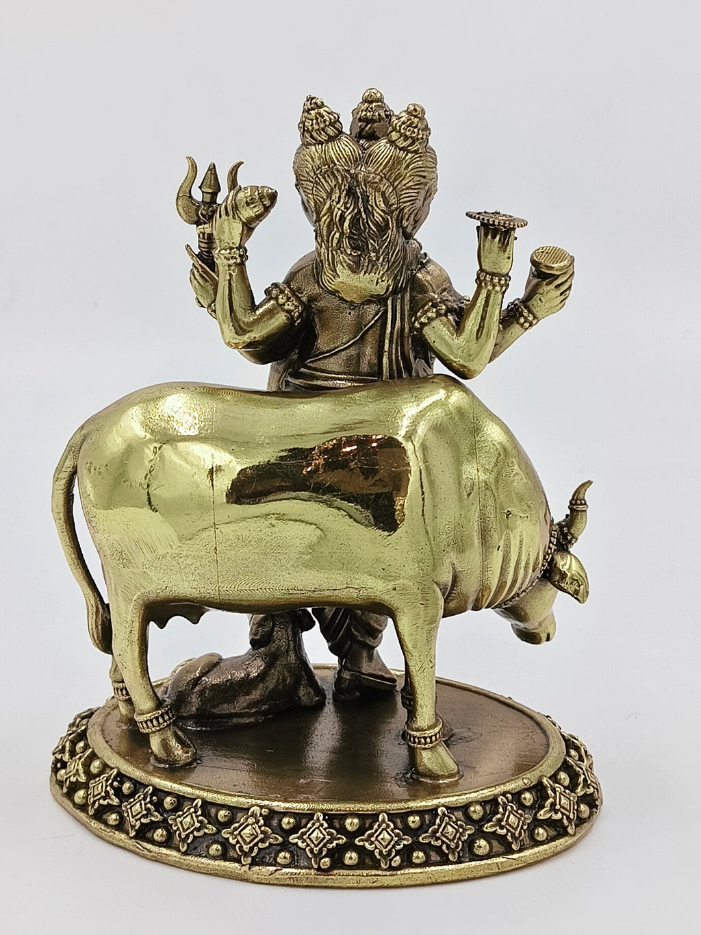 Rear view of medium brass Dattatreya statue featuring a cow and intricate base