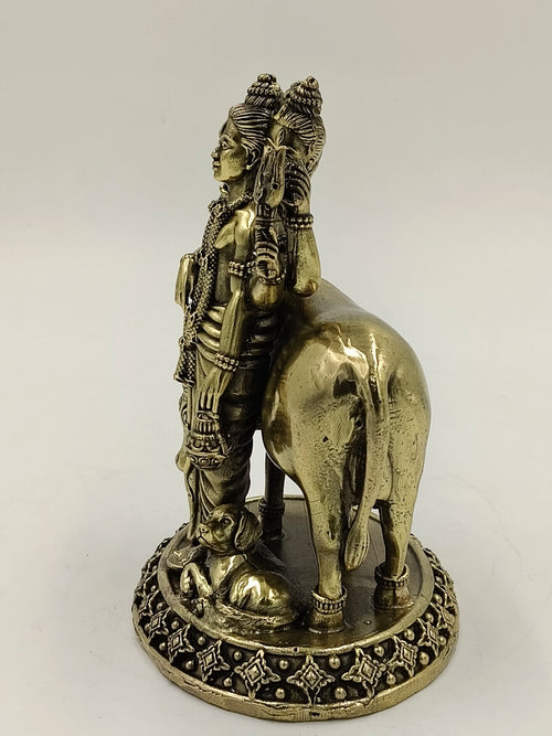 Side view of brass Dattatreya statue with cow and dog on decorative base
