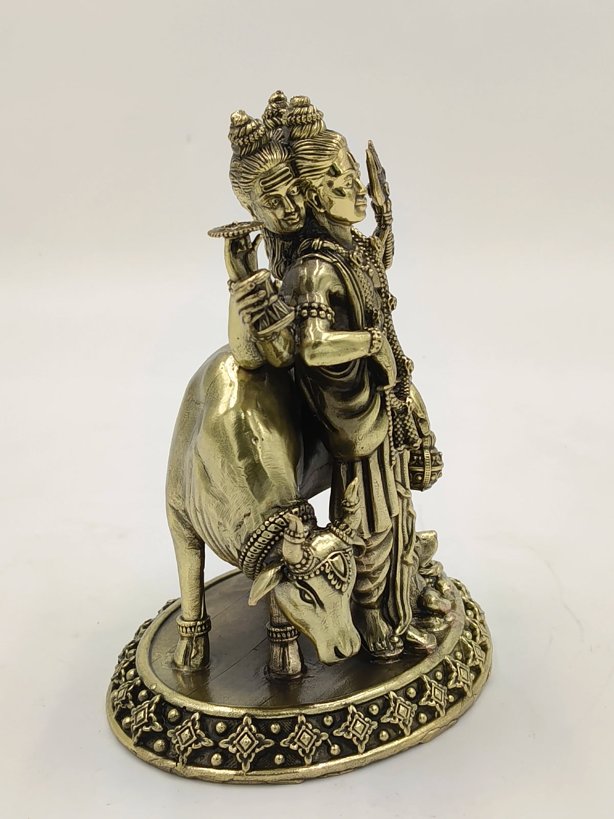 Brass statue of Dattatreya with three heads and a cow on decorative base