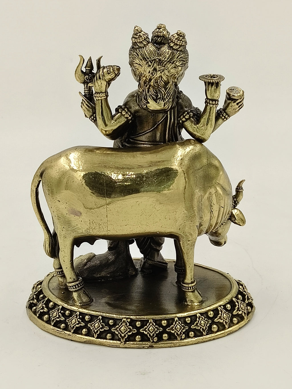 Rear view of medium brass Dattatreya statue with three heads and cow on decorative base