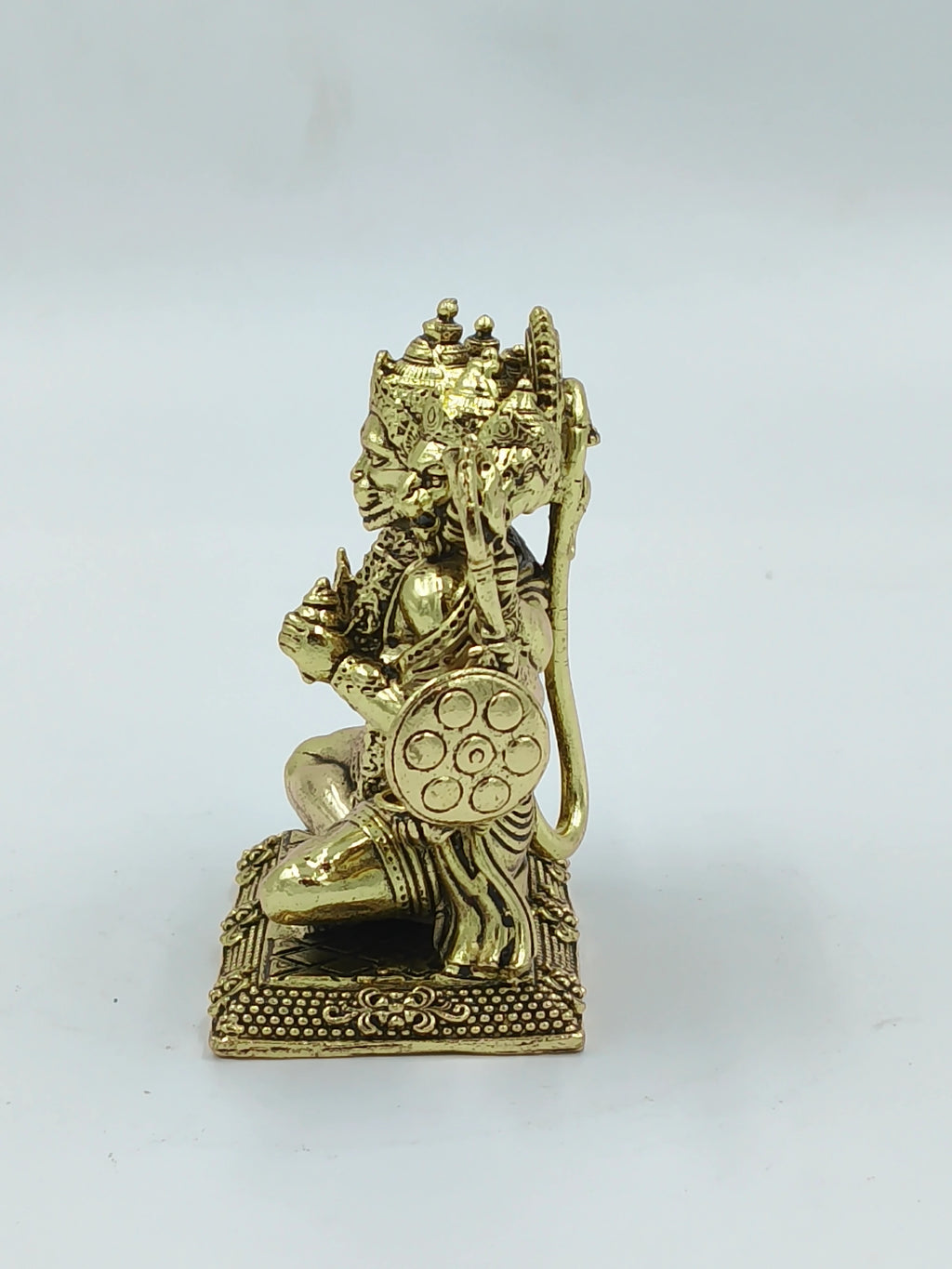Small brass Panchamukhi Hanuman statue kneeling on a decorative base, side view