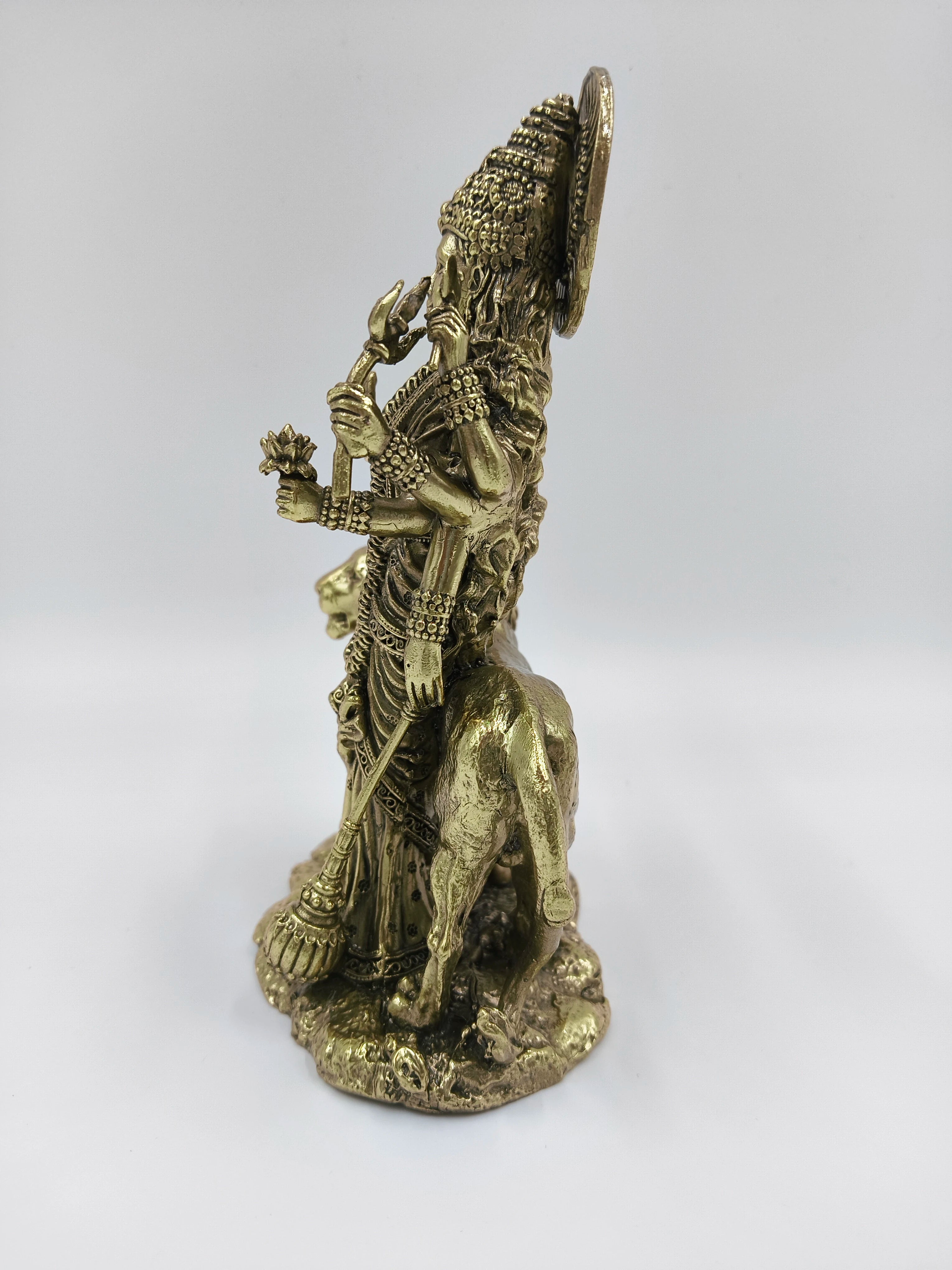 Side view of a medium brass Durgeshwari statue with multiple arms holding weapons