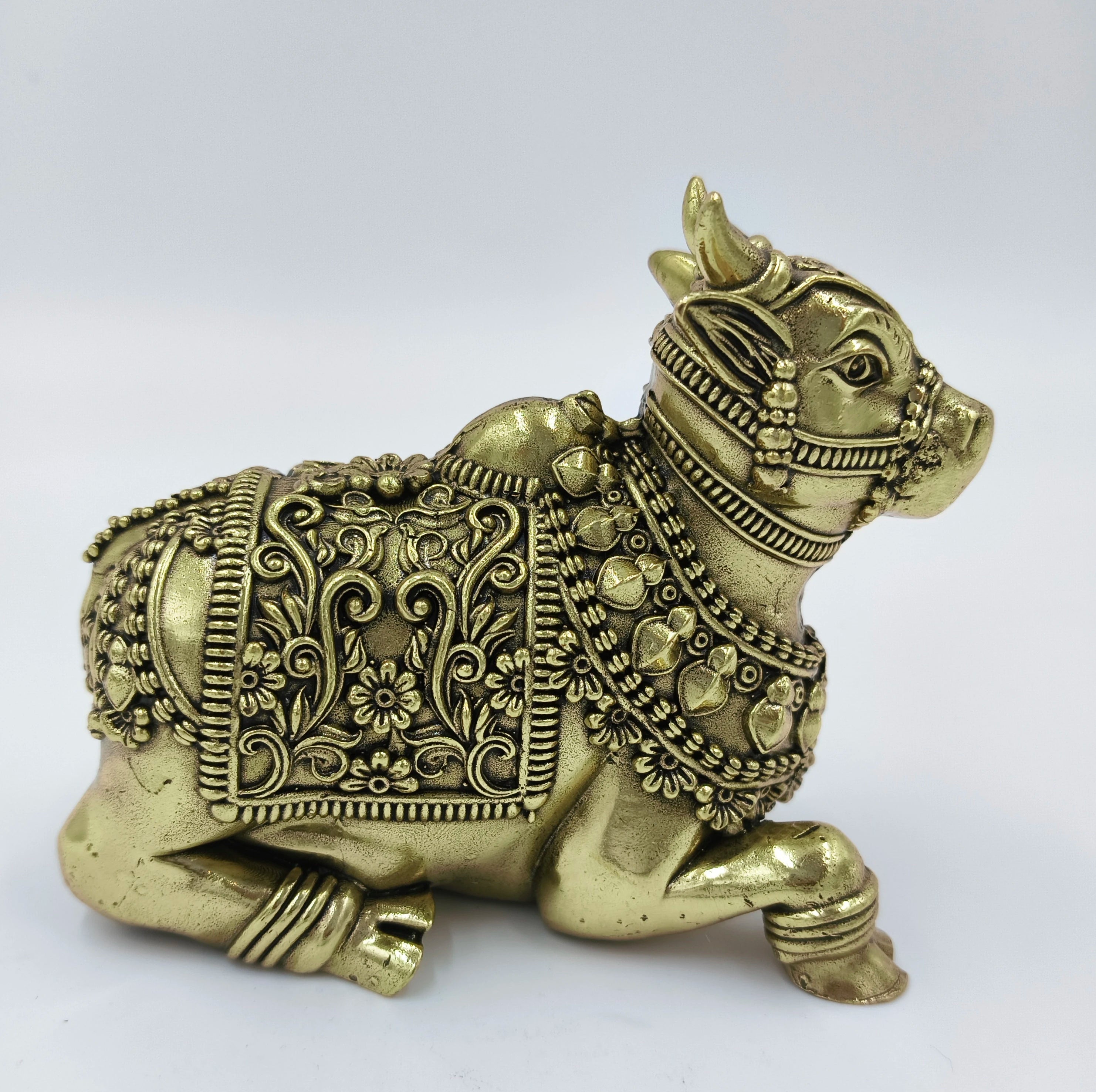 Brass statue of Nandhi bull with intricate floral designs, side view