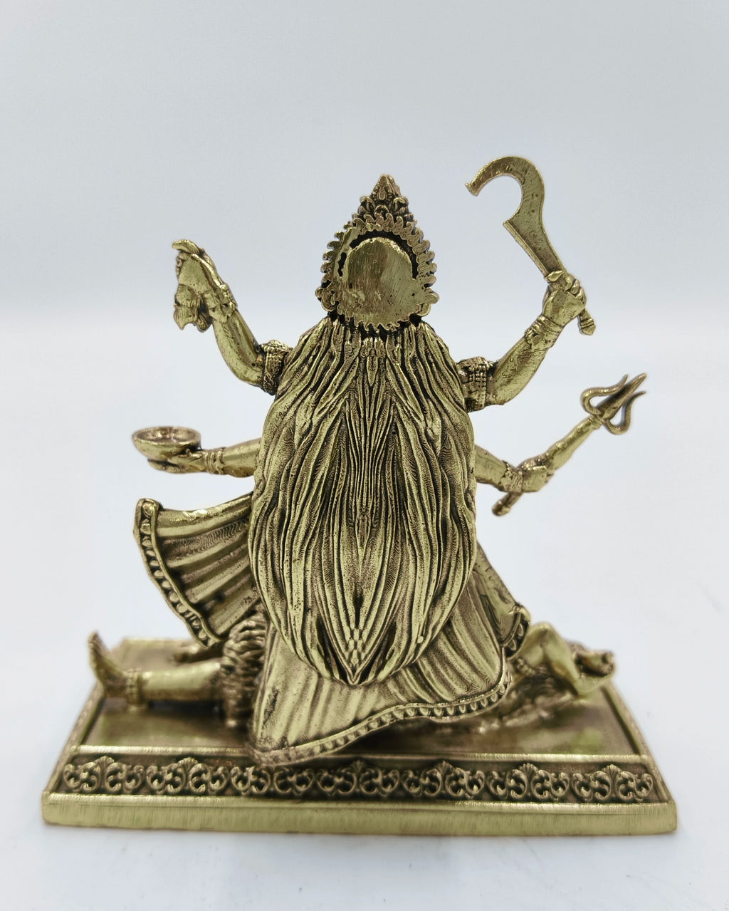 Back view of small brass Kalika deity sculpture with multiple arms on ornate base