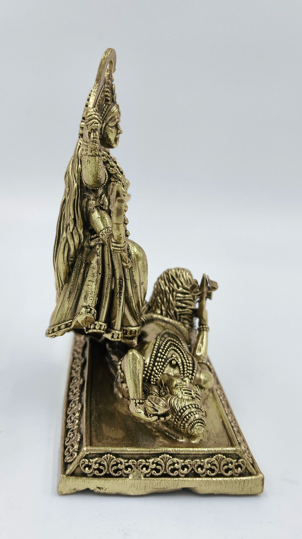 Side view of small brass Kalika deity statue on decorated base