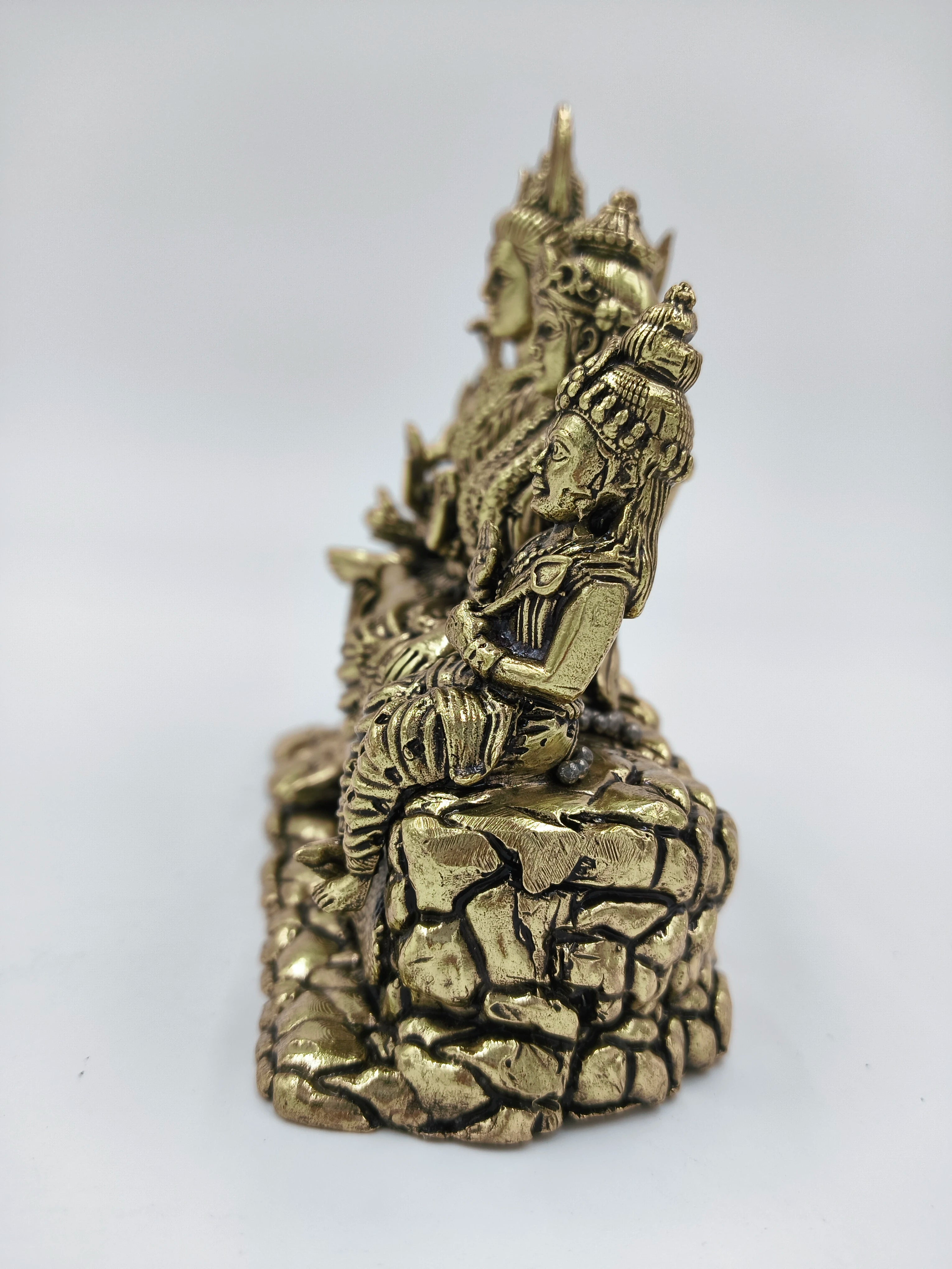 Side view of brass sculpture depicting Shiva with family seated on a rock