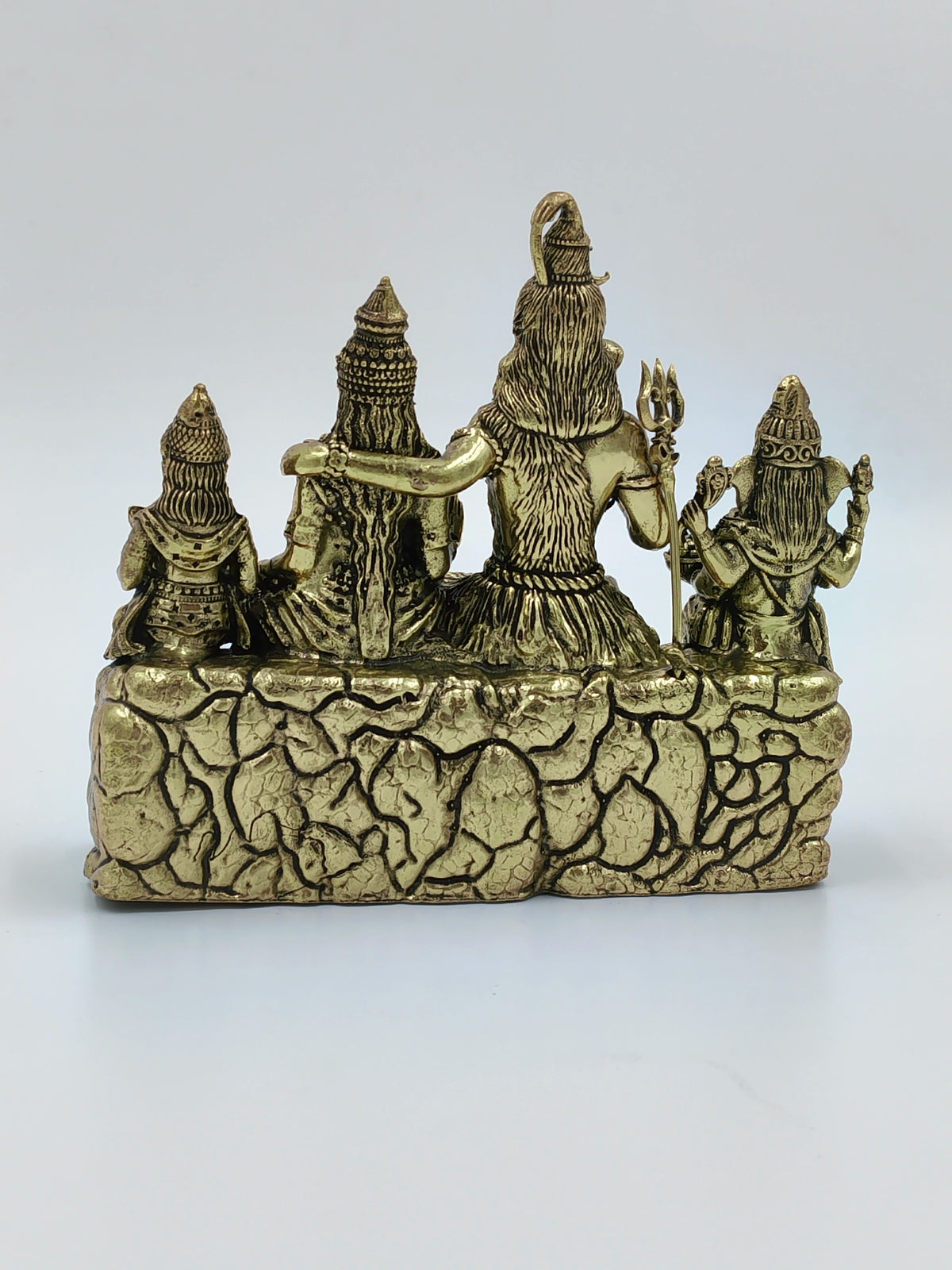 Back view of small brass sculpture depicting Shiva with family on a textured base