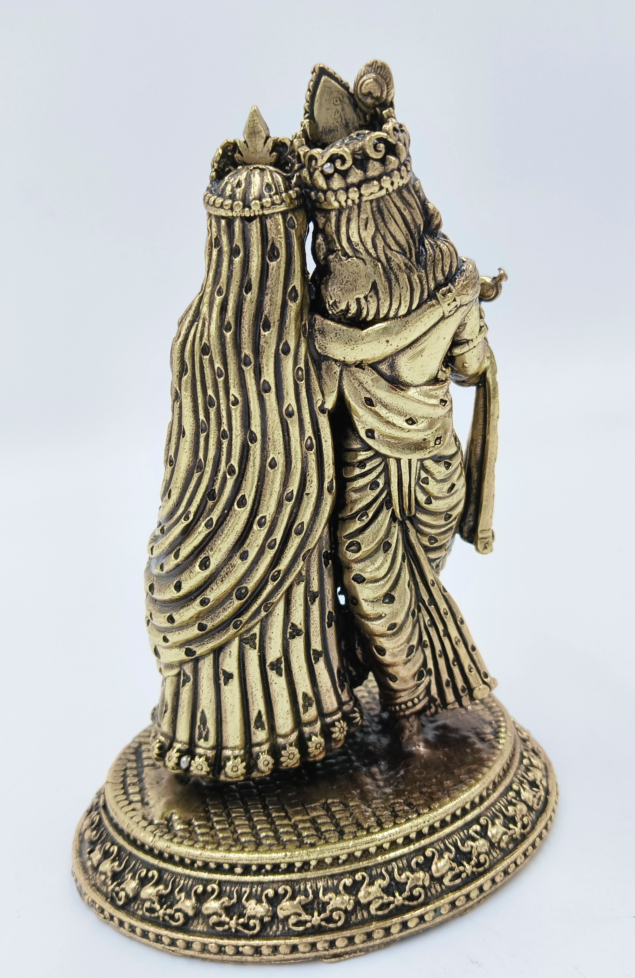 Back view of brass Radhakrishna sculpture with ornate details and decorative base