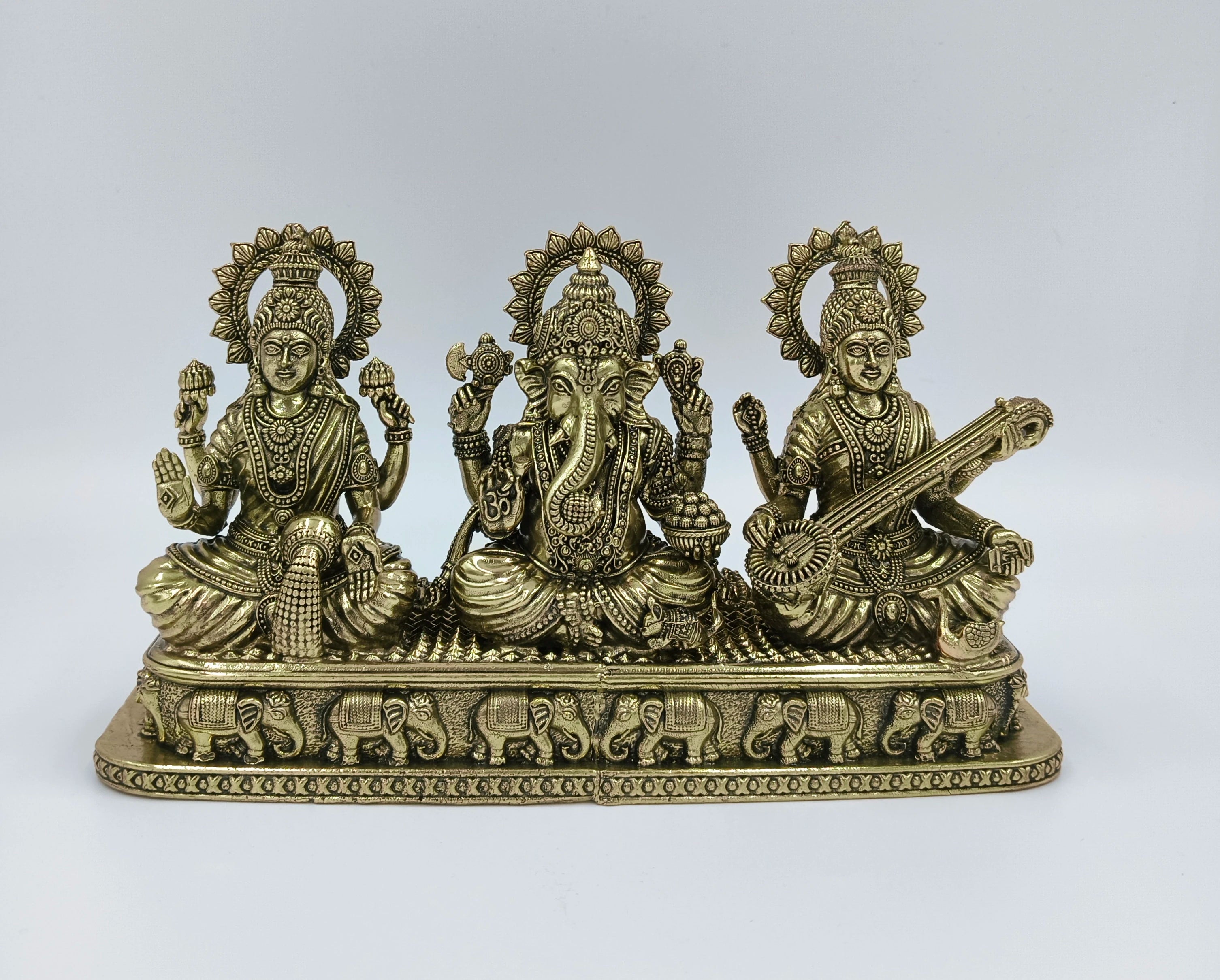Brass sculpture of Lakshmi, Ganesh, and Saraswathi seated on a decorative base