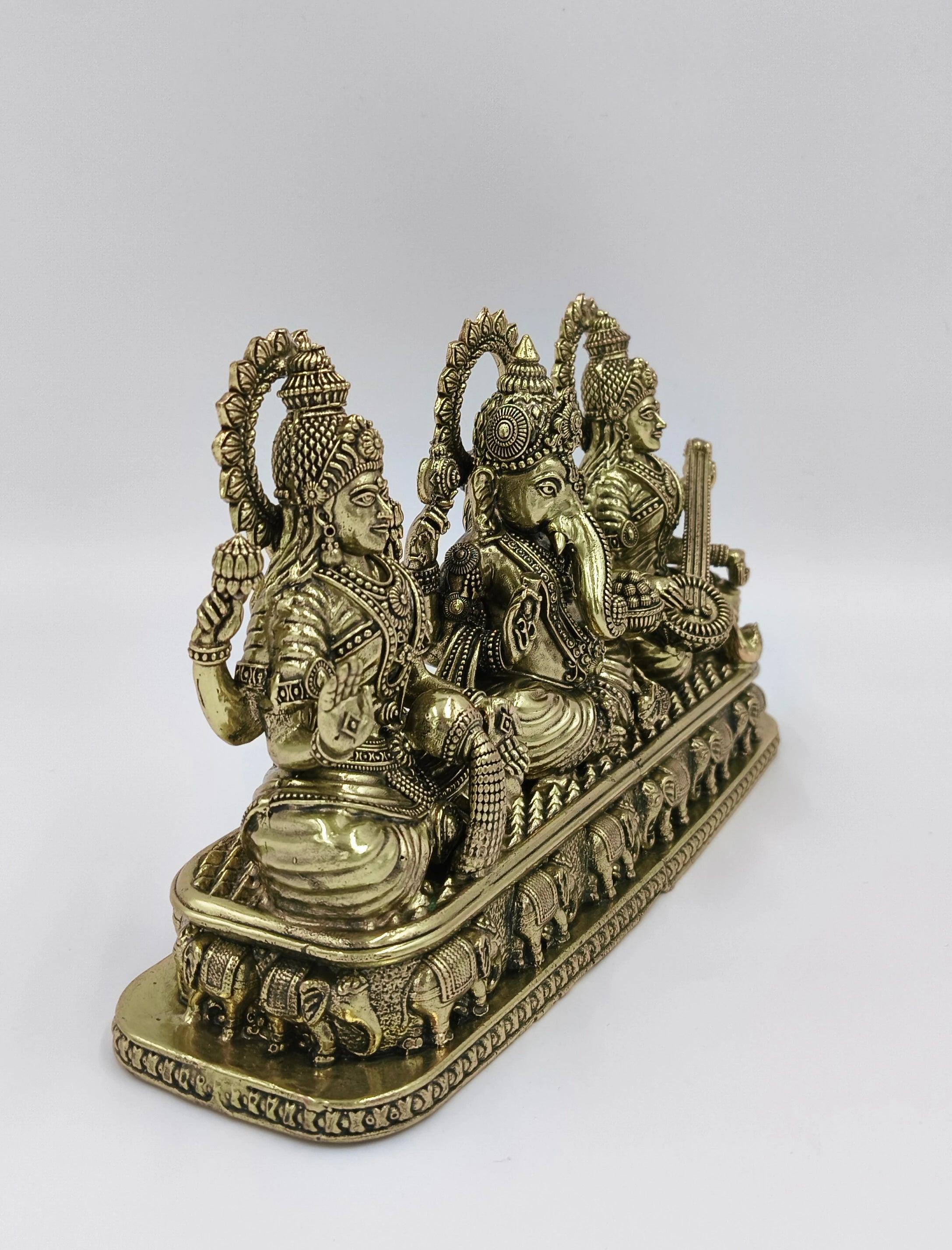 Brass sculpture of Lakshmi, Ganesh, and Saraswathi seated on an ornate base