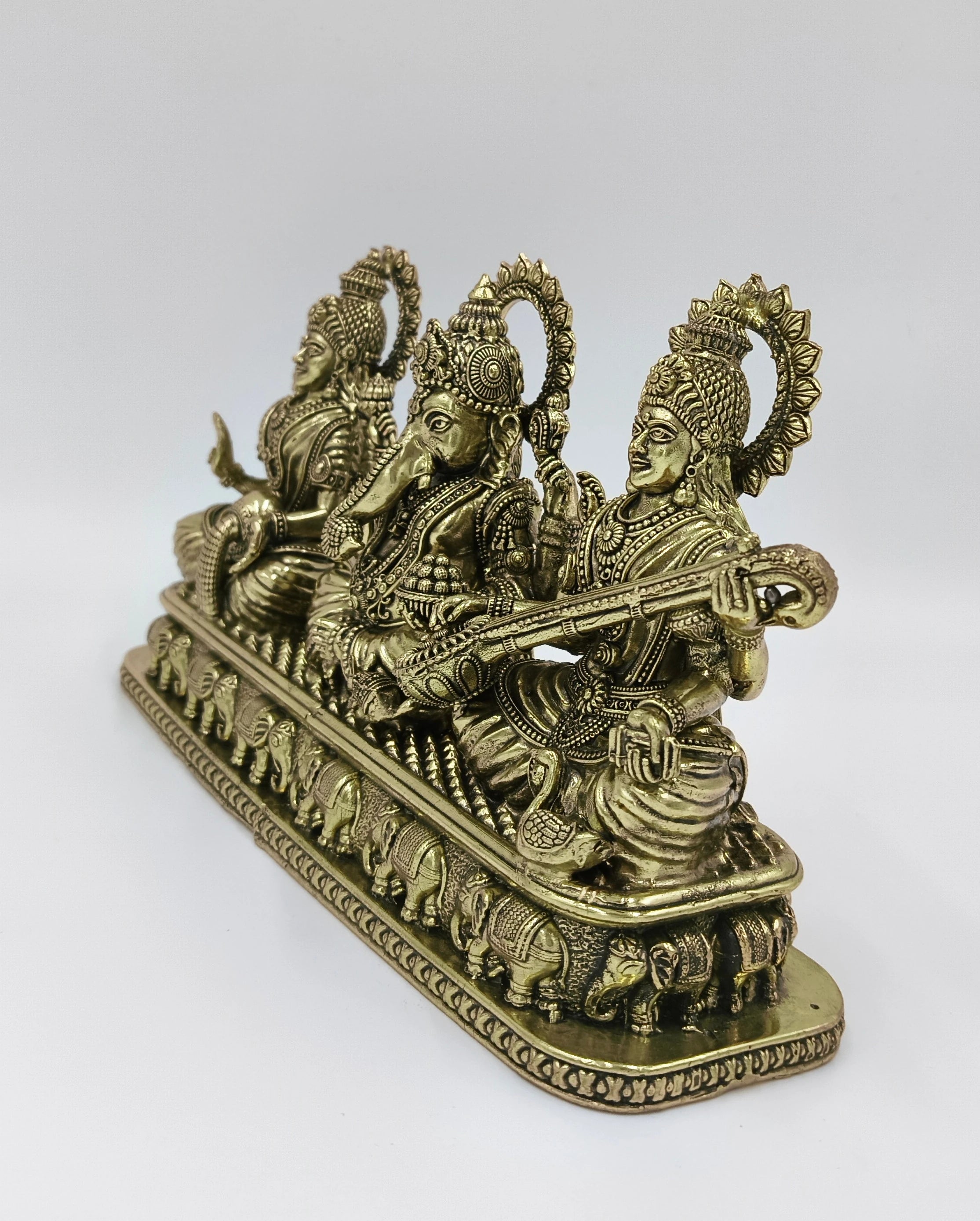 Brass sculpture of Lakshmi, Ganesh, and Saraswathi seated with detailed base
