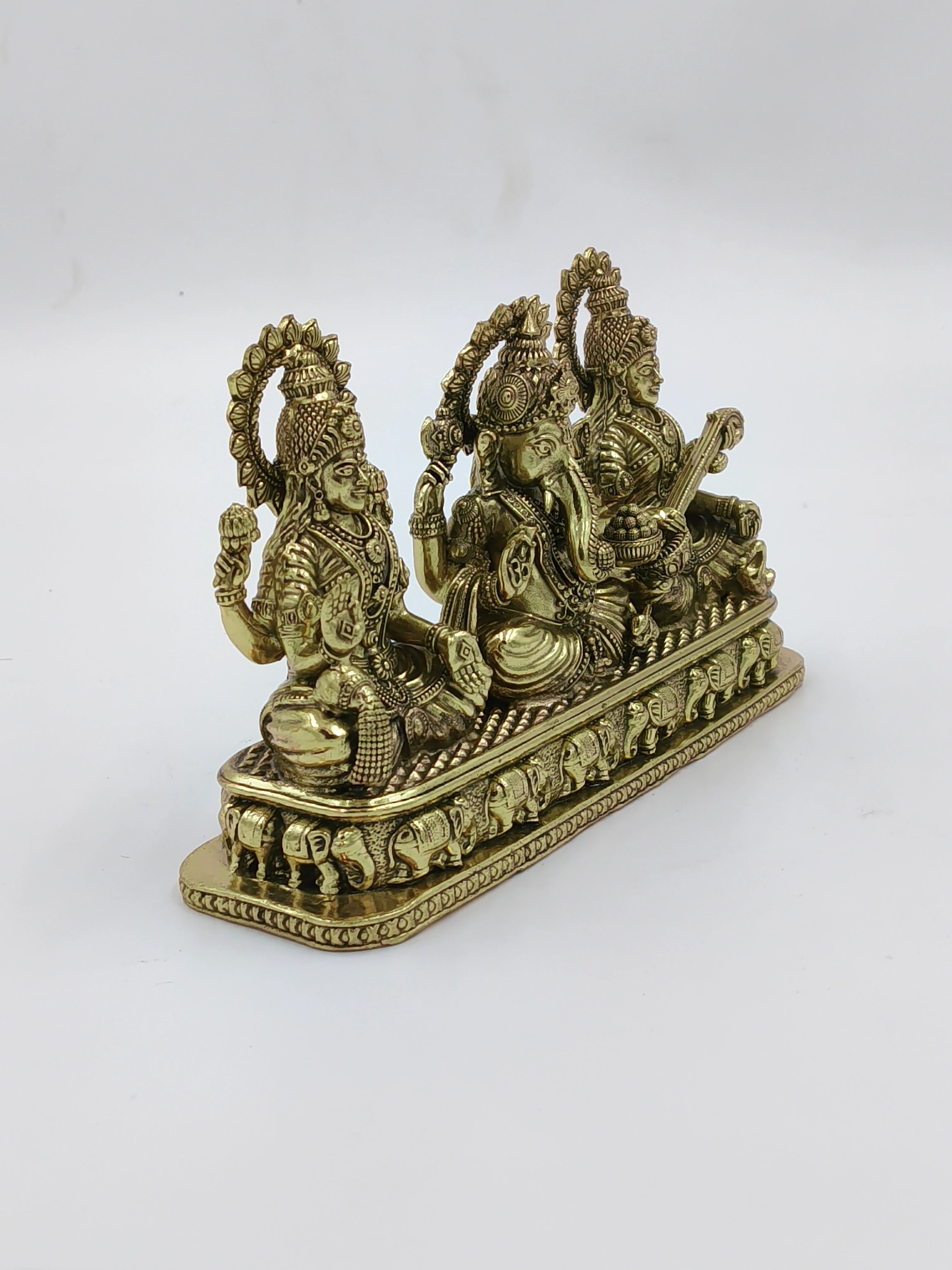 Brass sculpture of Lakshmi, Ganesh, and Saraswathi seated together on a decorative base