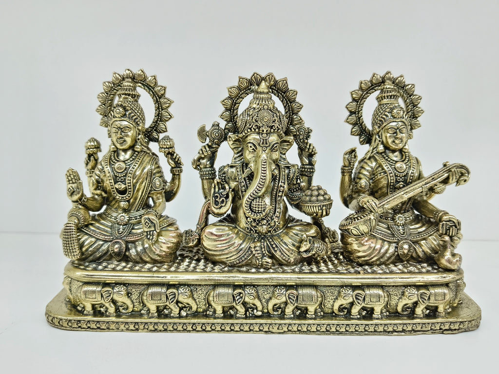 Small brass tabletop statue of Lakshmi, Ganesh, and Saraswathi with elephant motifs