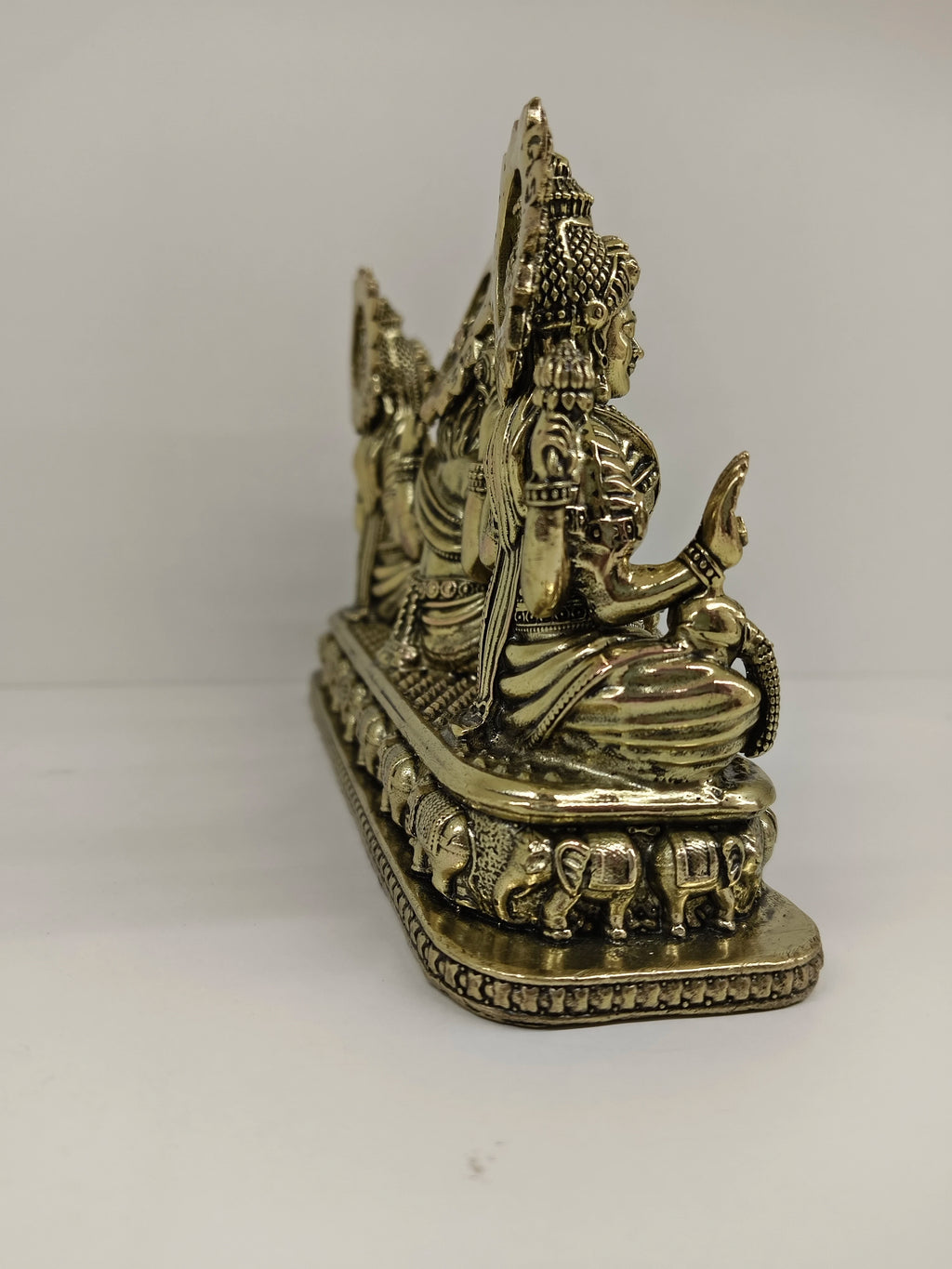 Side view of small brass Trayi Ashirwad statue with Lakshmi, Ganesh, and Saraswathi