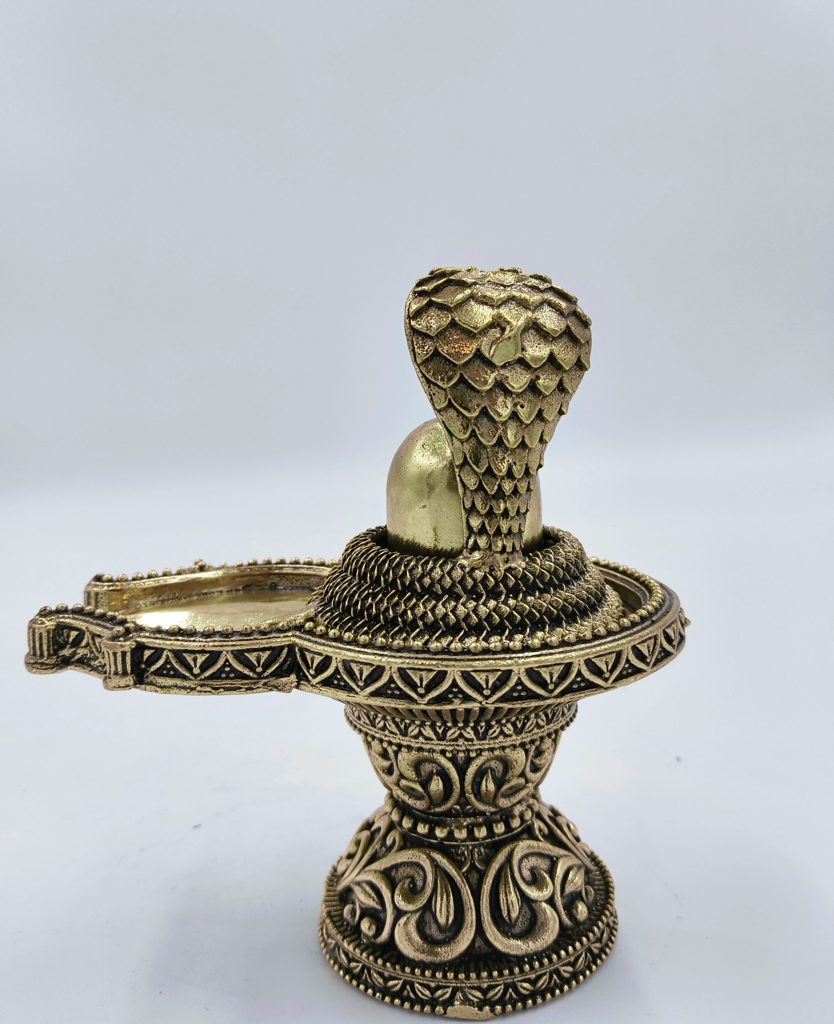Medium brass Shivalinga sculpture with ornate base and serpent hood detail side view